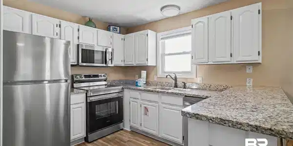 Image 3: Kitchen featuring stainless steel appliances, white cabinetry, light stone countertops, a peninsula, and light wood-style floors