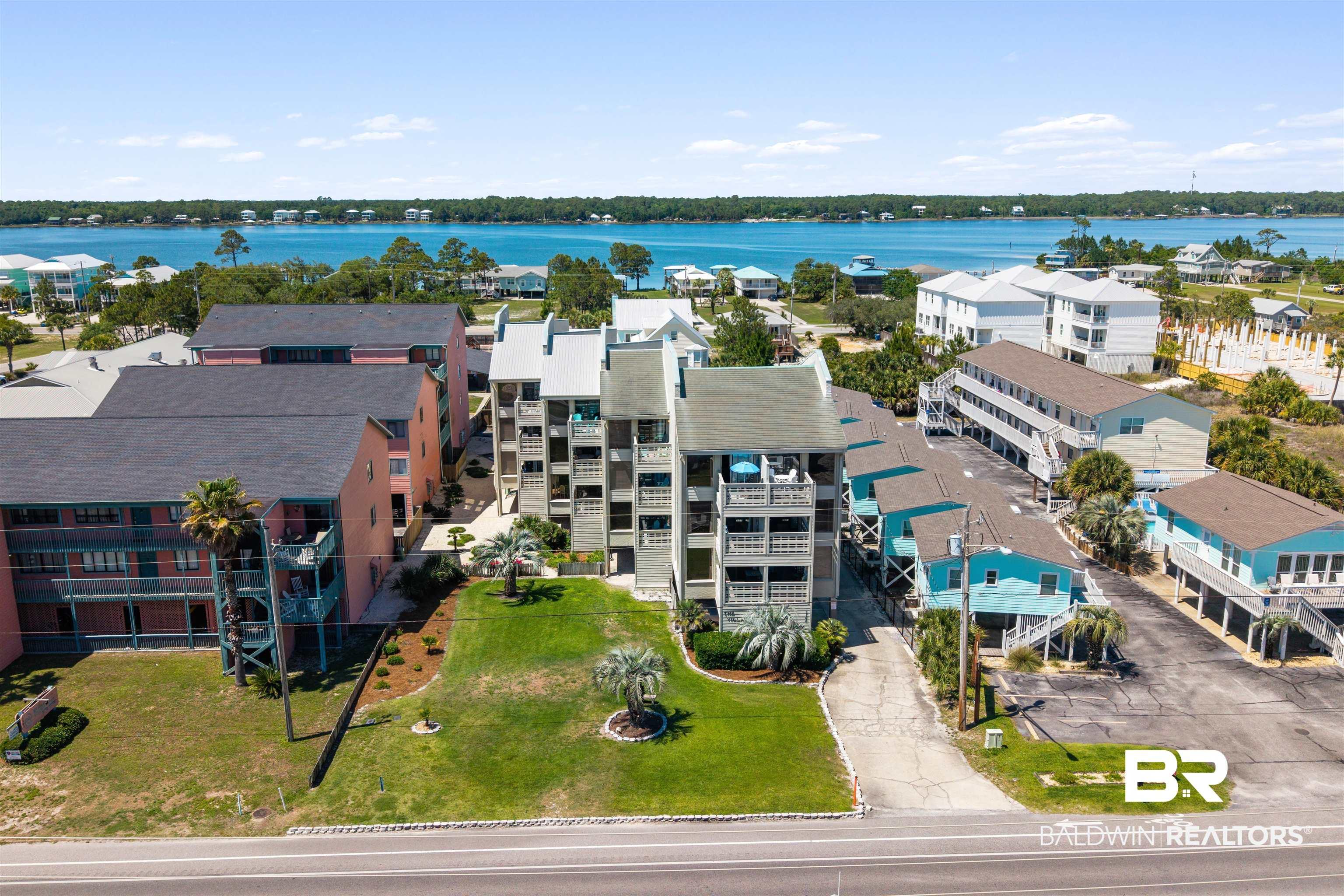 Image 1: Multi-story coastal residential property featuring multiple balconies, mature palm trees, and a manicured lawn