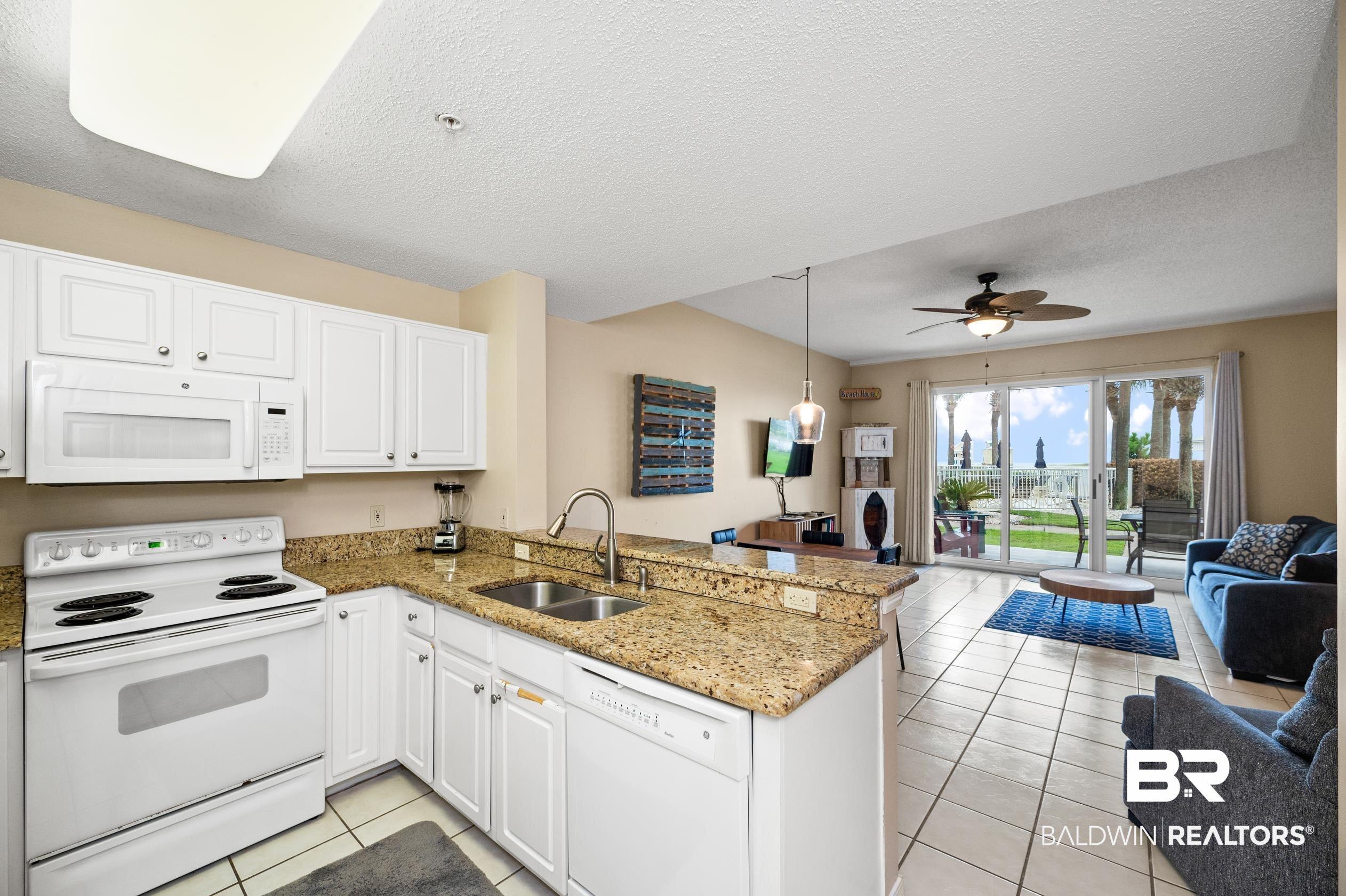Image 2: Kitchen featuring white appliances, light tile patterned floors, a peninsula, a sink, and open floor plan