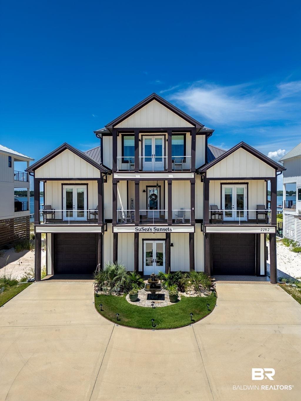 Image 1: View of front of property with french doors, a balcony, board and batten siding, and an attached garage