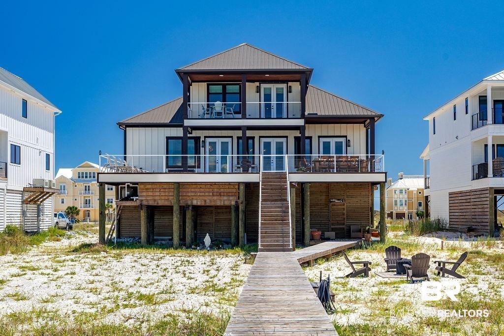 Image 3: Rear view of house featuring a balcony, french doors, board and batten siding, a fire pit, and stairs