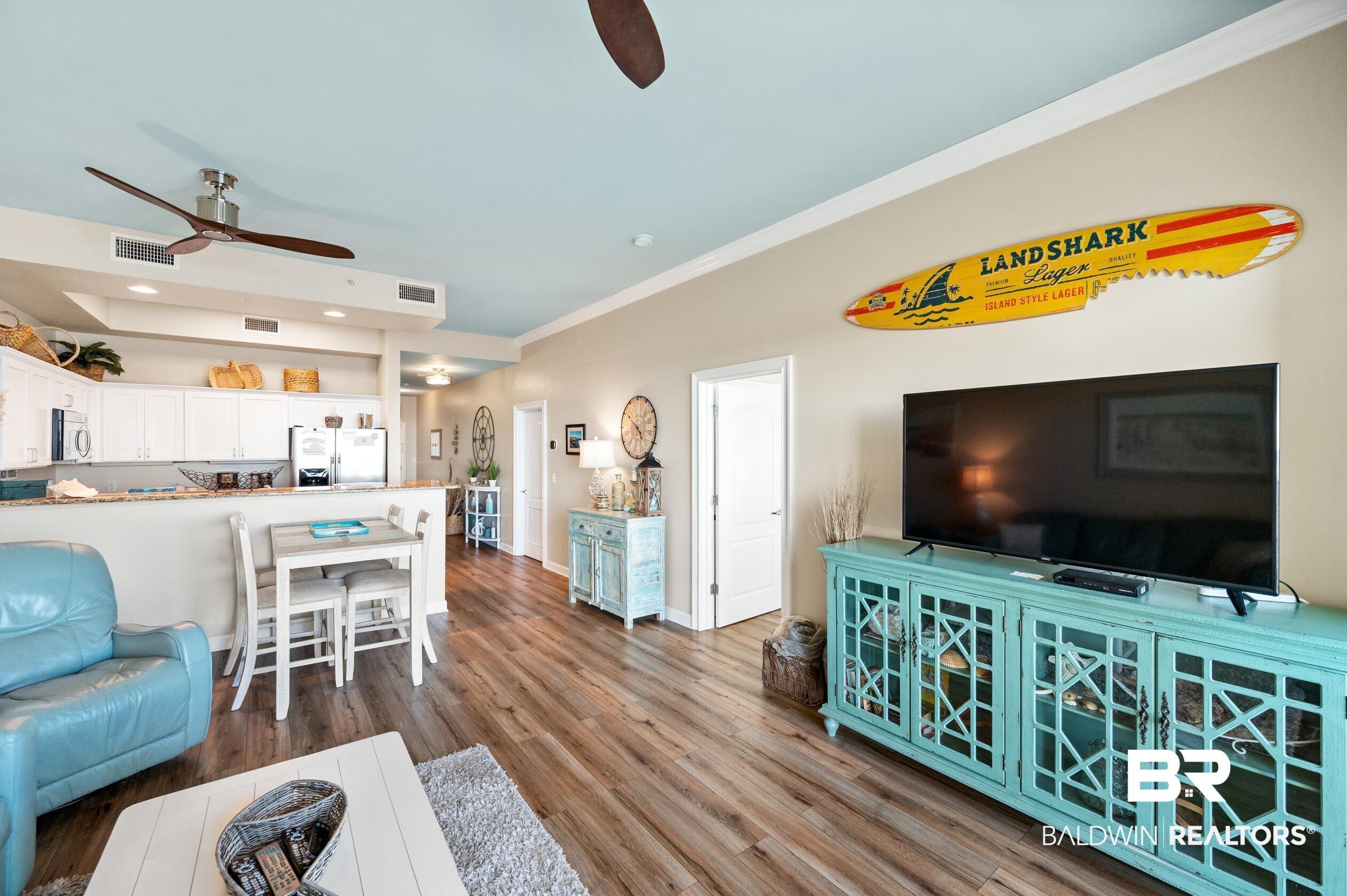Image 2: Living area featuring crown molding, visible vents, ceiling fan, and wood finished floors