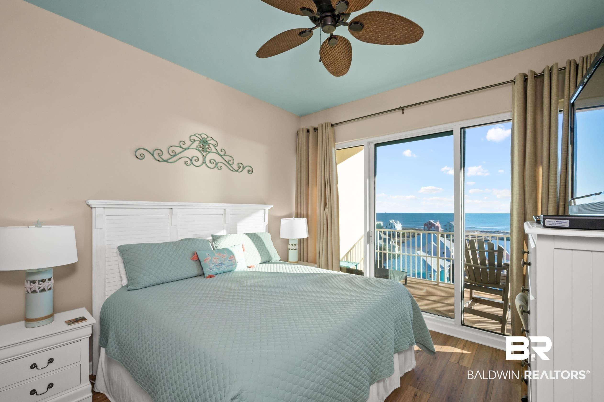 Image 3: Bedroom with access to exterior, a ceiling fan, and dark wood-style floors