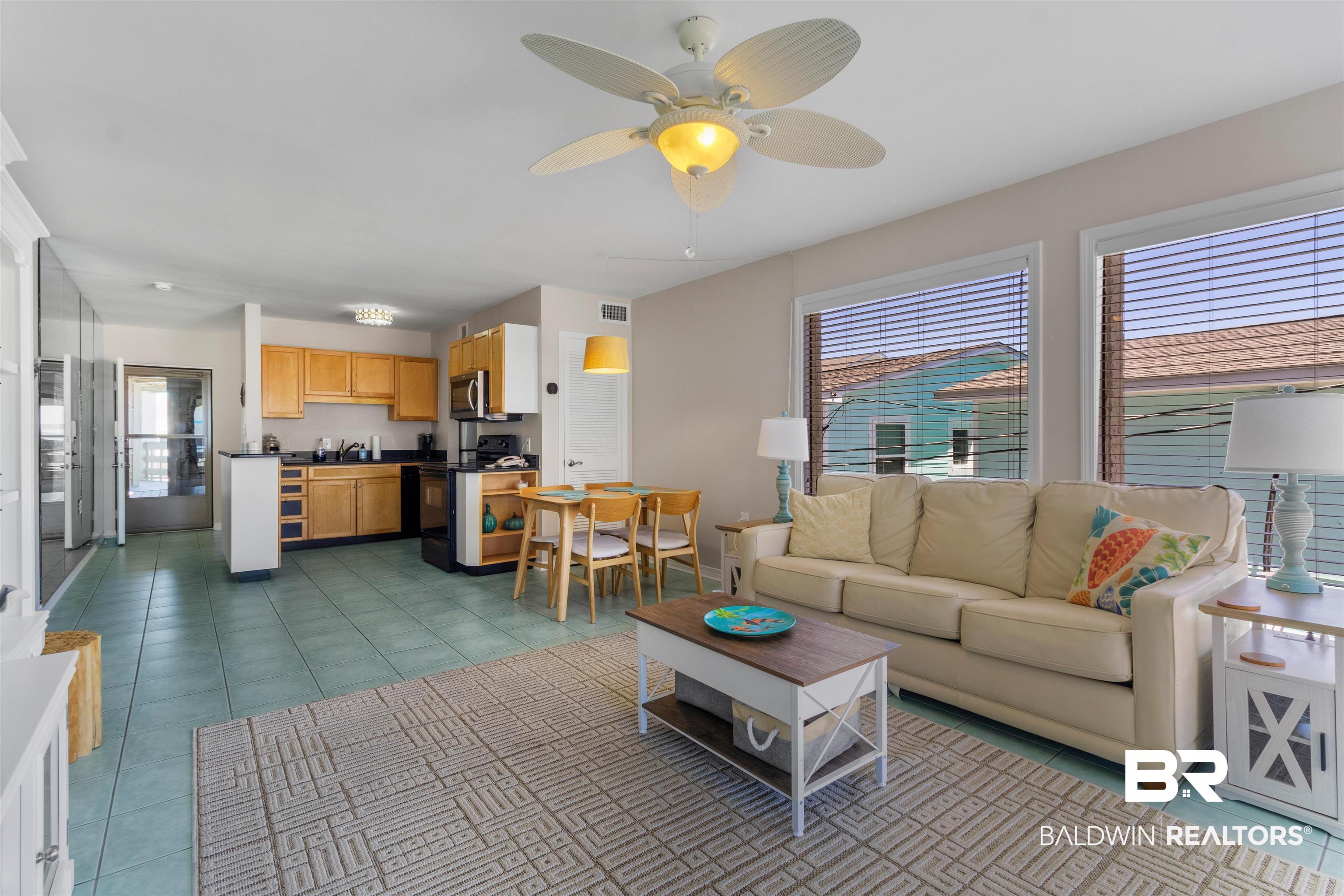 Image 2: Open-concept living space featuring light-colored walls, tile flooring, and a ceiling fan