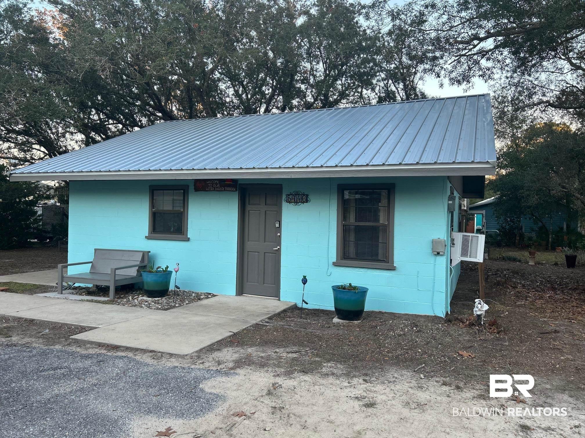 Image 4: Turquoise exterior with a light grey metal roof