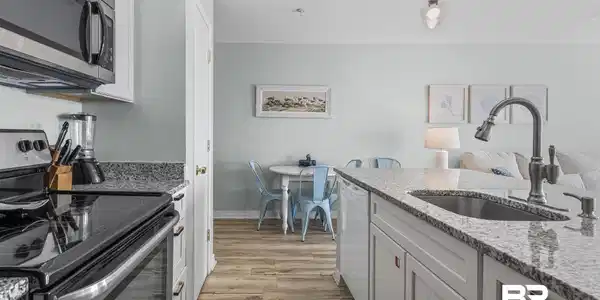 Image 3: Kitchen with stainless steel appliances, white cabinetry, light stone countertops, pendant lighting, and light wood-style floors