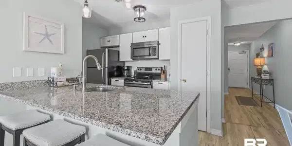 Image 4: Kitchen featuring a breakfast bar area, stainless steel appliances, a peninsula, light stone counters, and white cabinets