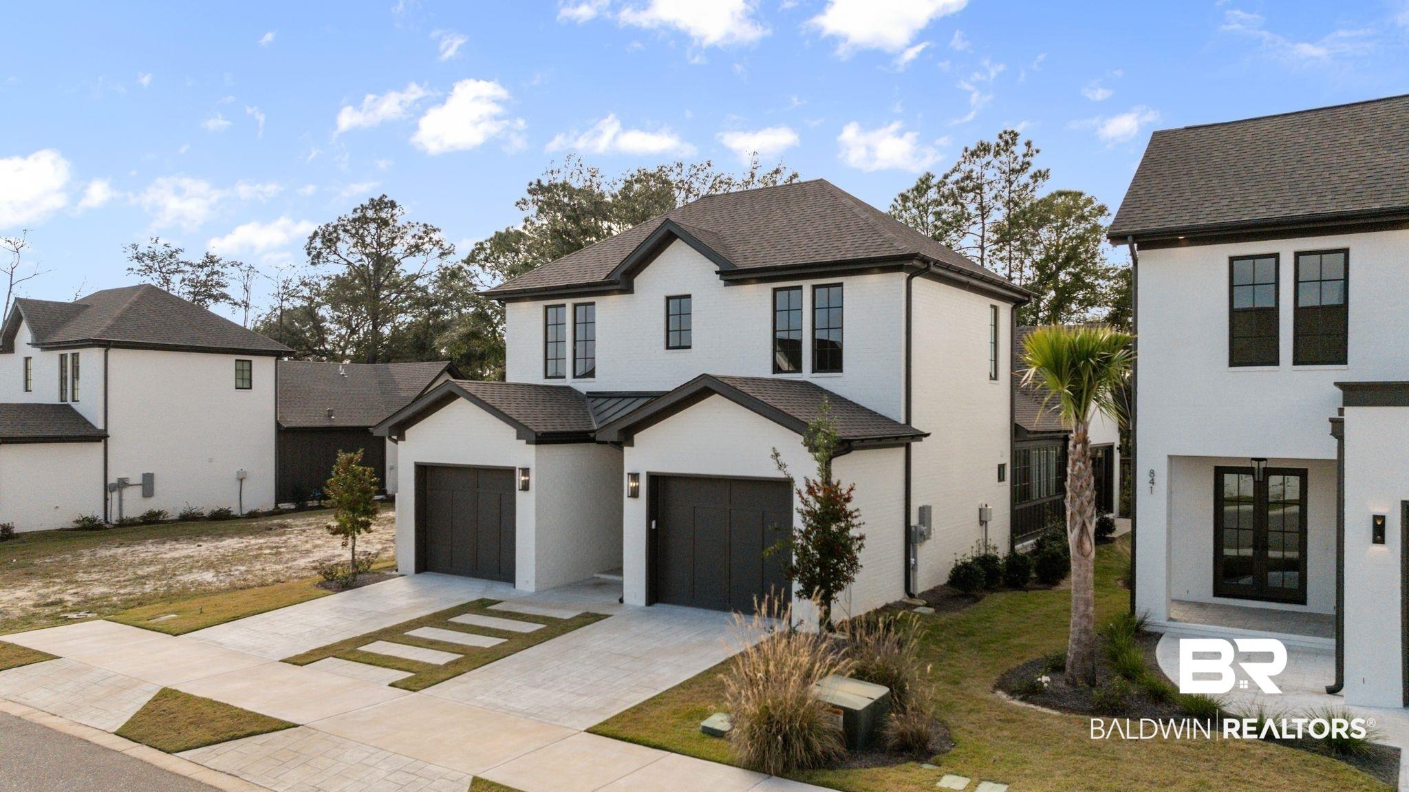 Image 2: Modern inspired farmhouse with decorative driveway, a front lawn, brick siding, and an attached garage