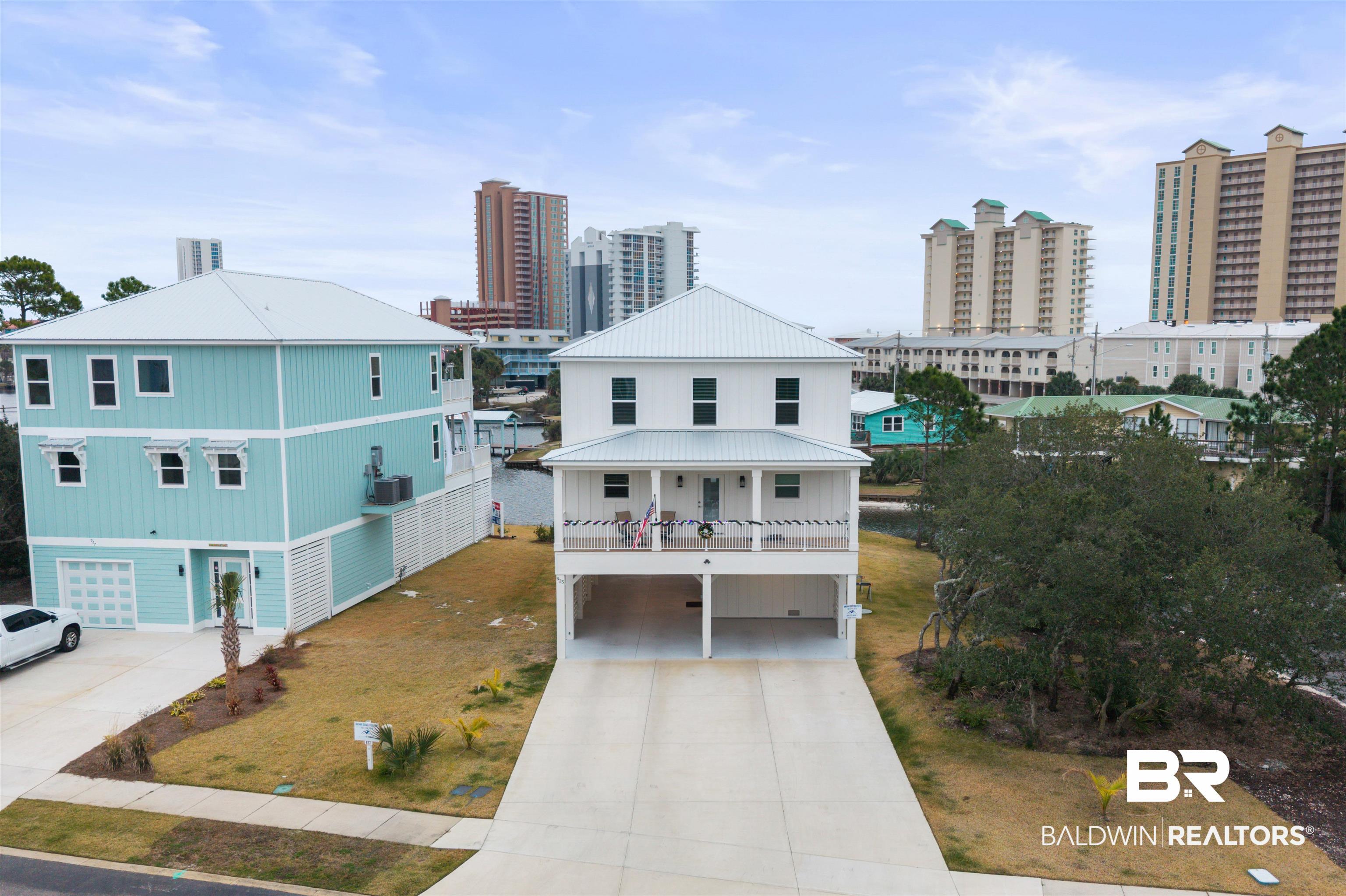 Image 1: View of front of property with concrete driveway, a view of city, a carport, a balcony, and a metal roof
