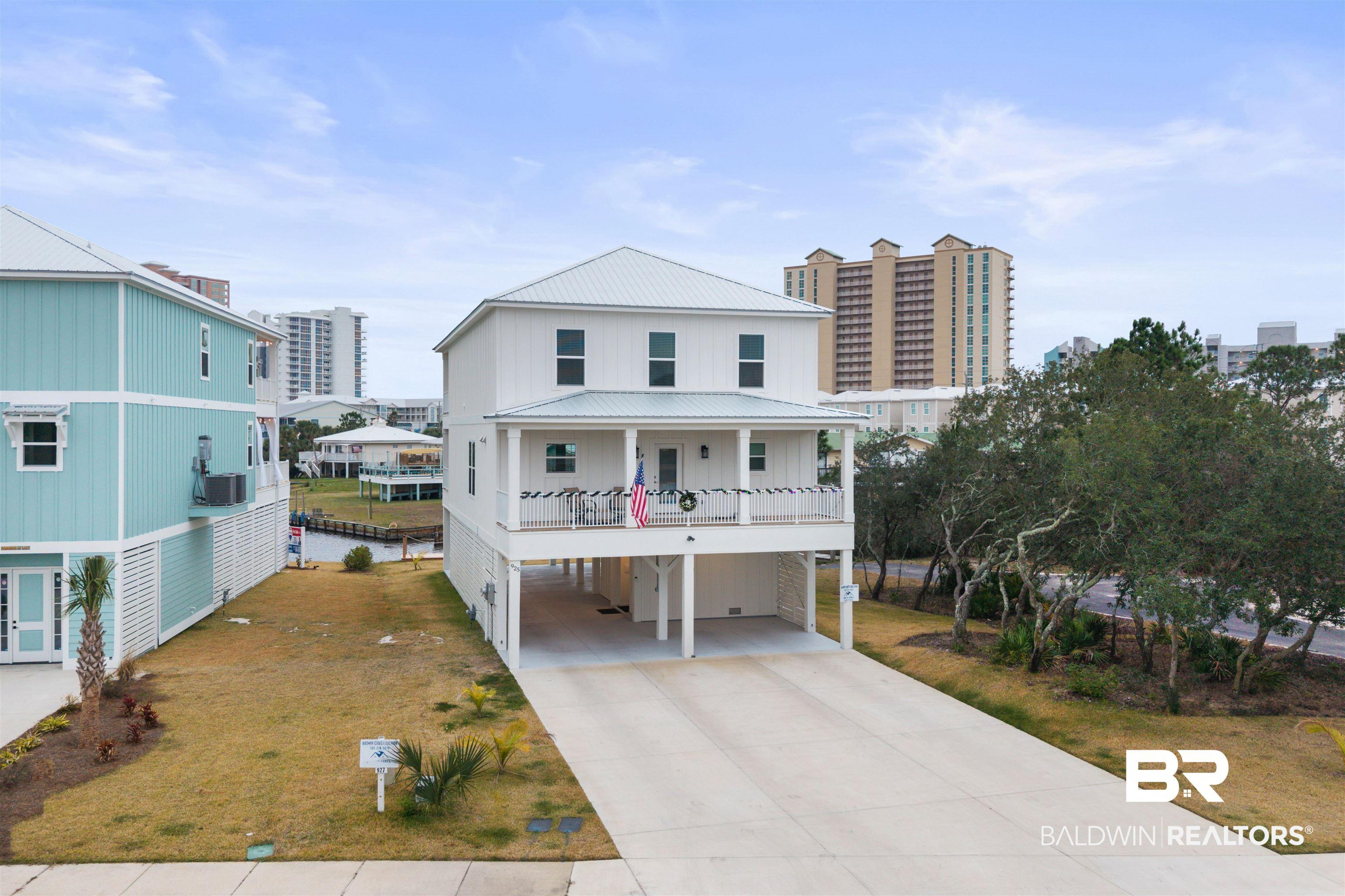 Image 2: Beach home featuring a carport, driveway, a metal roof, board and batten siding, and covered porch