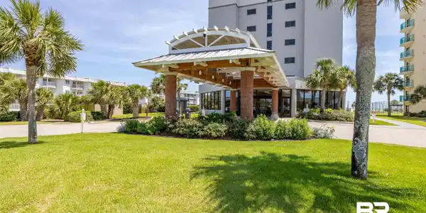 Image 3: Building entrance featuring a covered drive, brick columns, and a landscaped island
