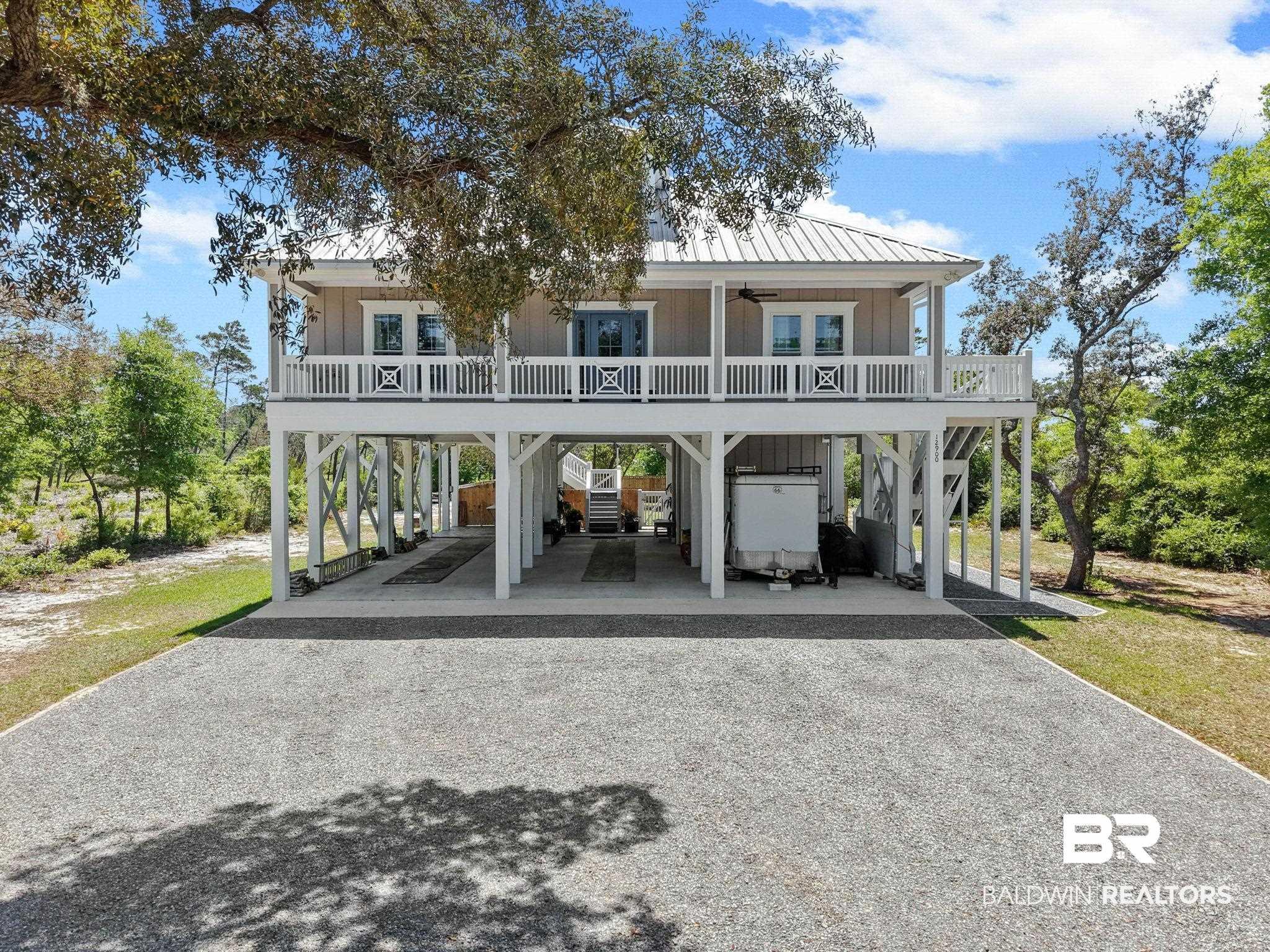 Image 2: Back of property featuring board and batten siding, ceiling fan, gravel driveway, and a carport