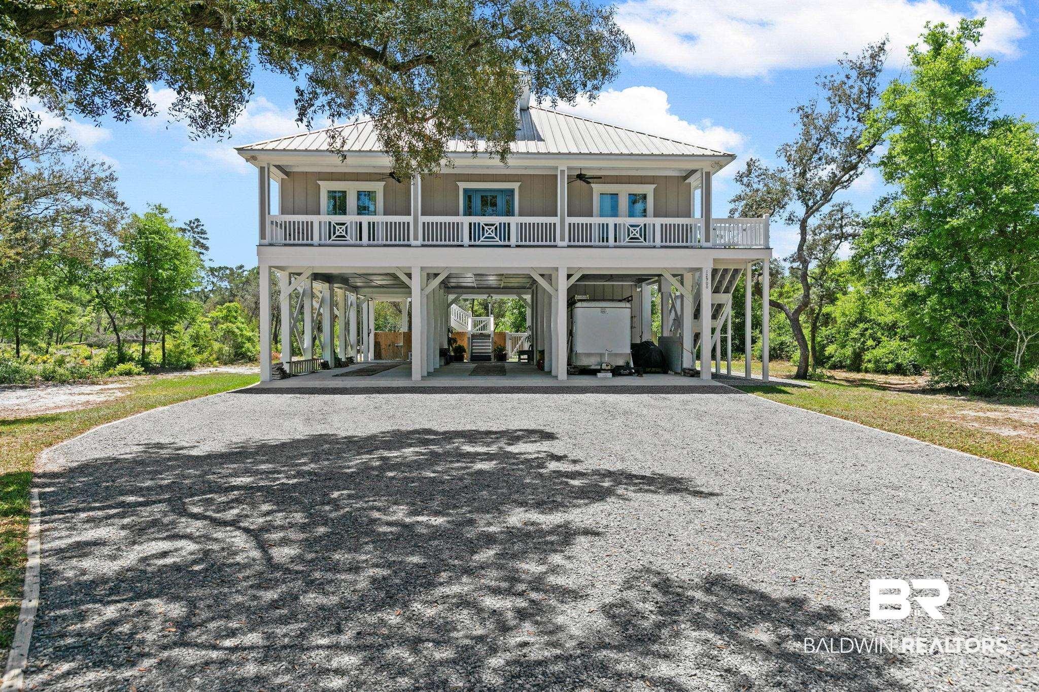 Image 3: Coastal home with a carport, driveway, ceiling fan, a metal roof, and board and batten siding