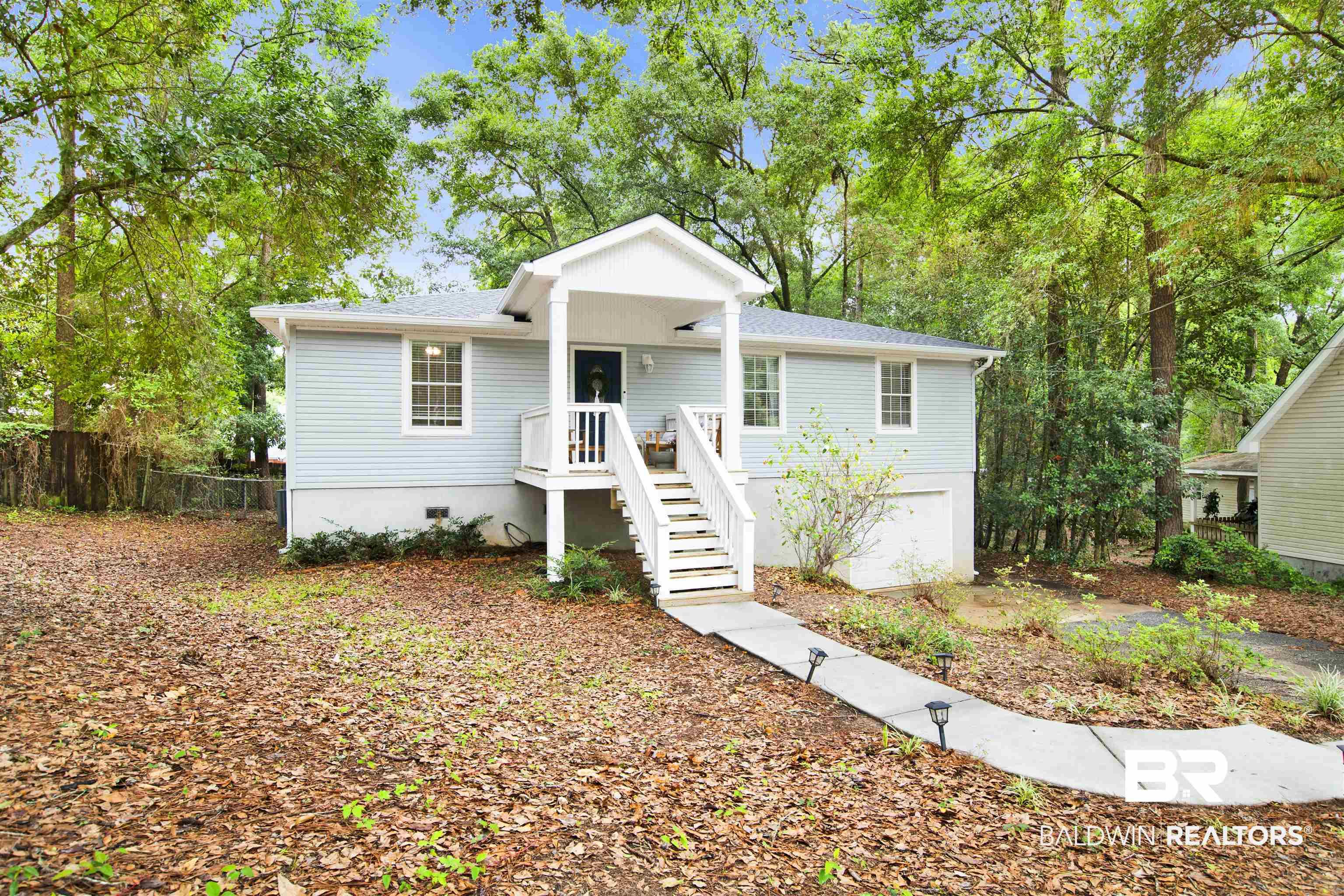Image 2: Light blue siding exterior featuring a white covered porch with railing and steps, white window trim, and a concrete pathway with small light fixtures