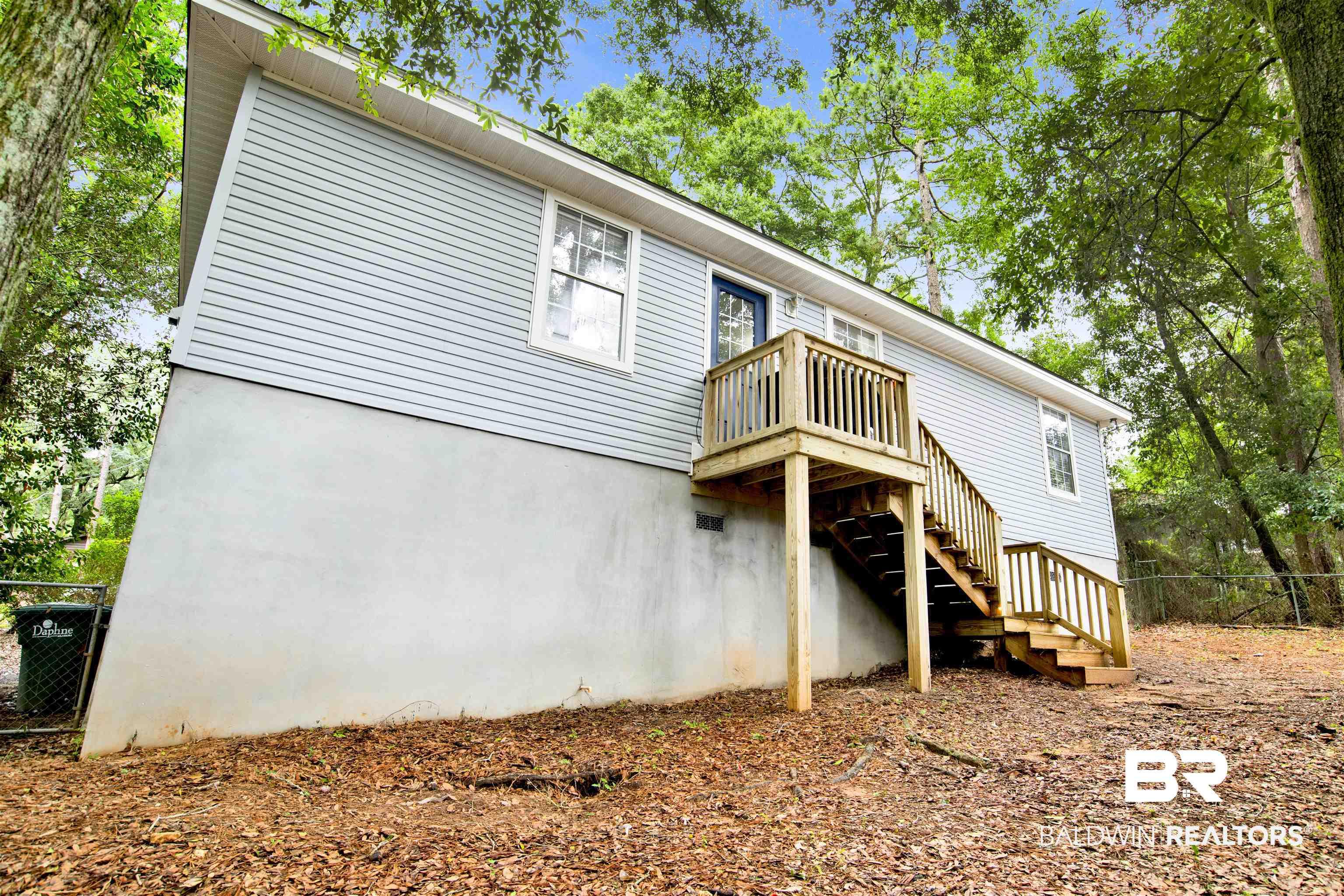 Image 3: Rear exterior featuring light blue horizontal siding and a two-story wooden deck with stairs
