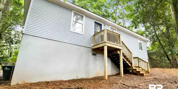Image 3: Rear exterior featuring light blue horizontal siding and a two-story wooden deck with stairs