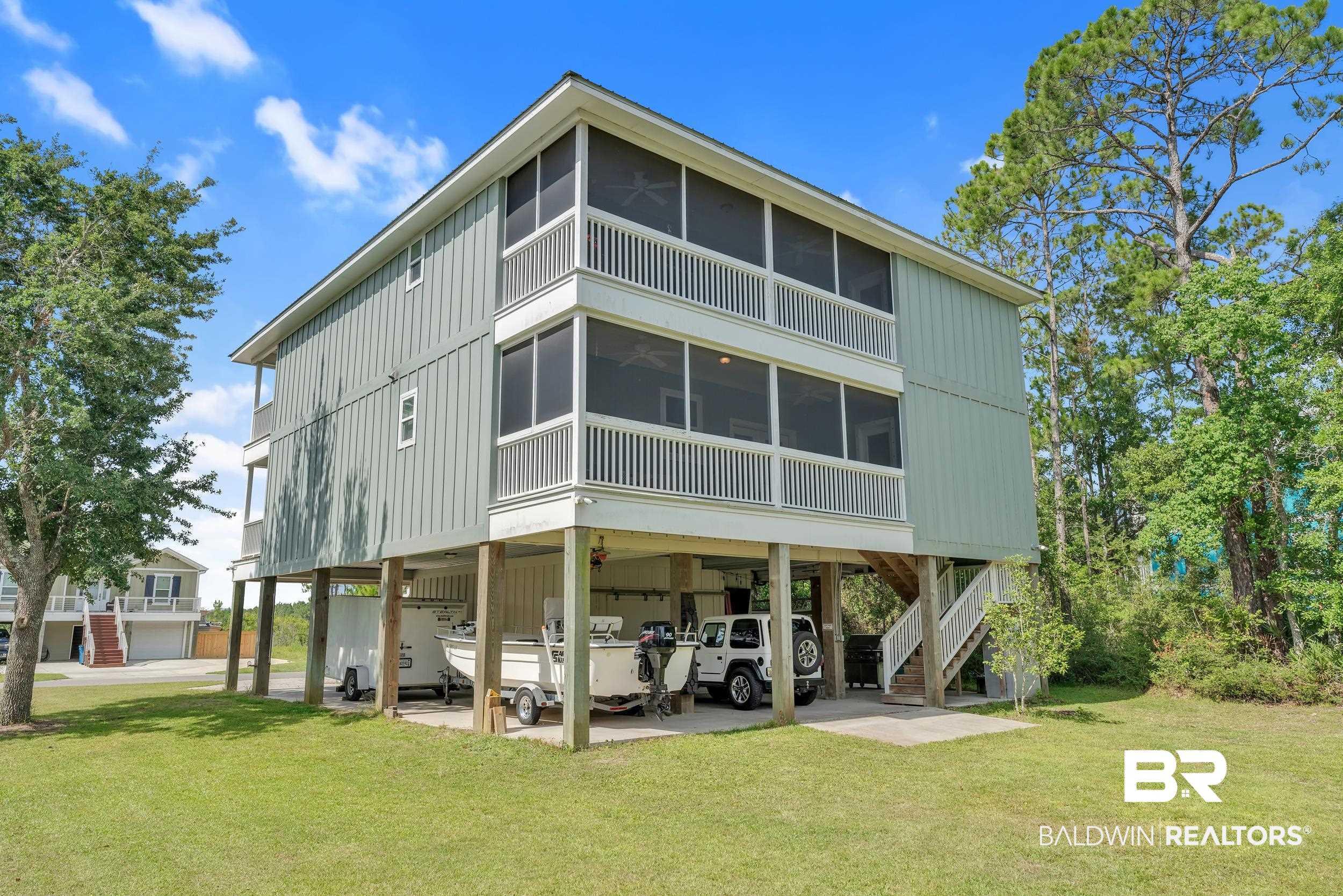 Image 4: Rear view of property with a sunroom, a carport, stairway, and a lawn
