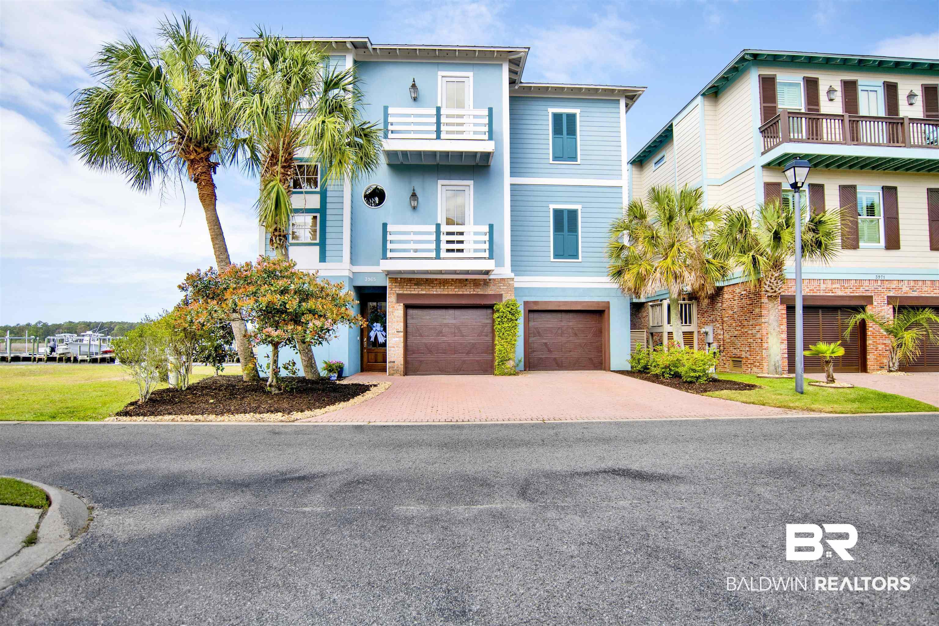 Image 1: Beach home featuring decorative driveway, a garage, brick siding, and a balcony