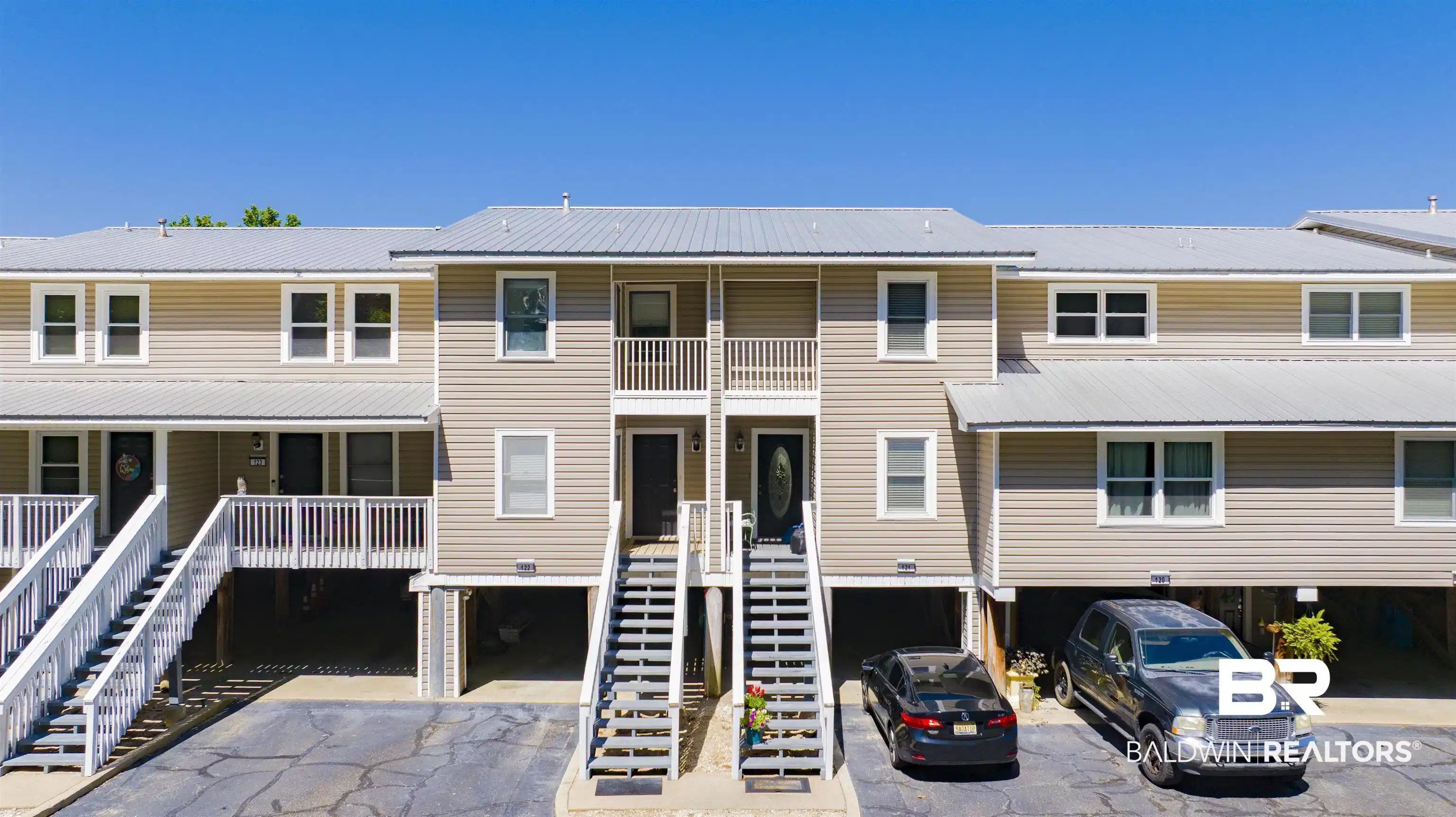 Image 1: Multi-story residential building featuring light brown siding and a metal roof