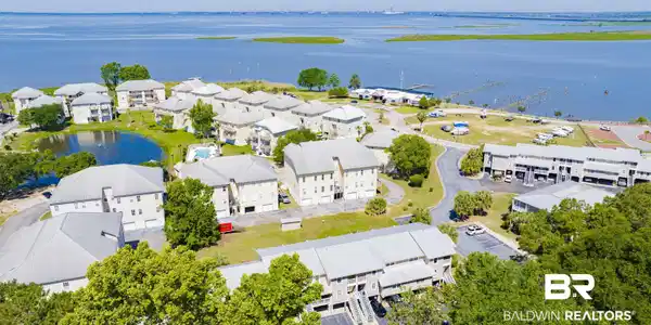 Image 2: Expansive waterfront community featuring multiple residential buildings, a central pond, and a community swimming pool