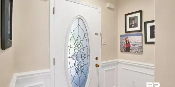 Image 4: Entry door with an oval leaded glass insert, brass hardware, and white trim
