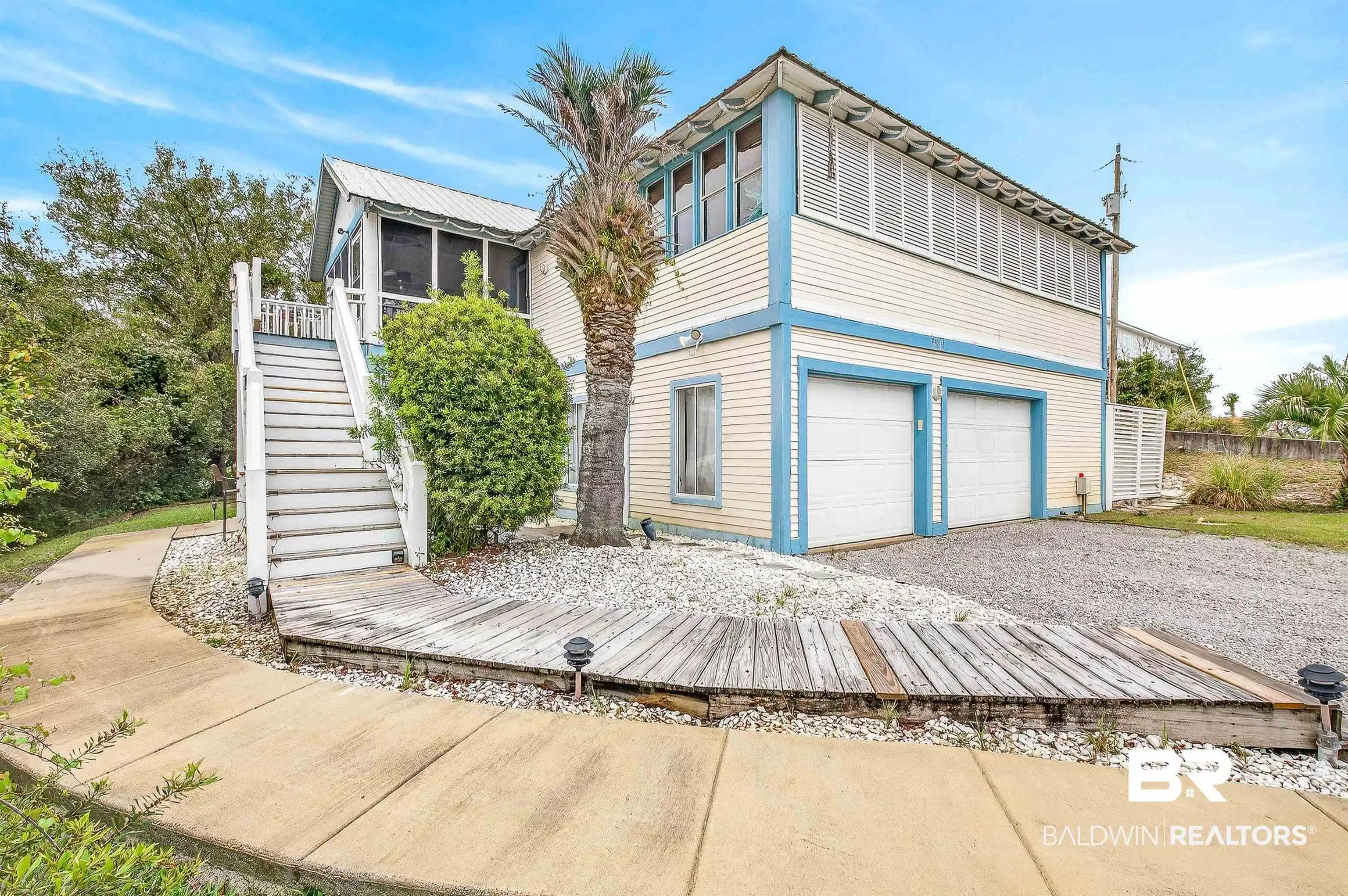 Image 1: View of front of home with a wooden deck, a garage, a sunroom, and driveway