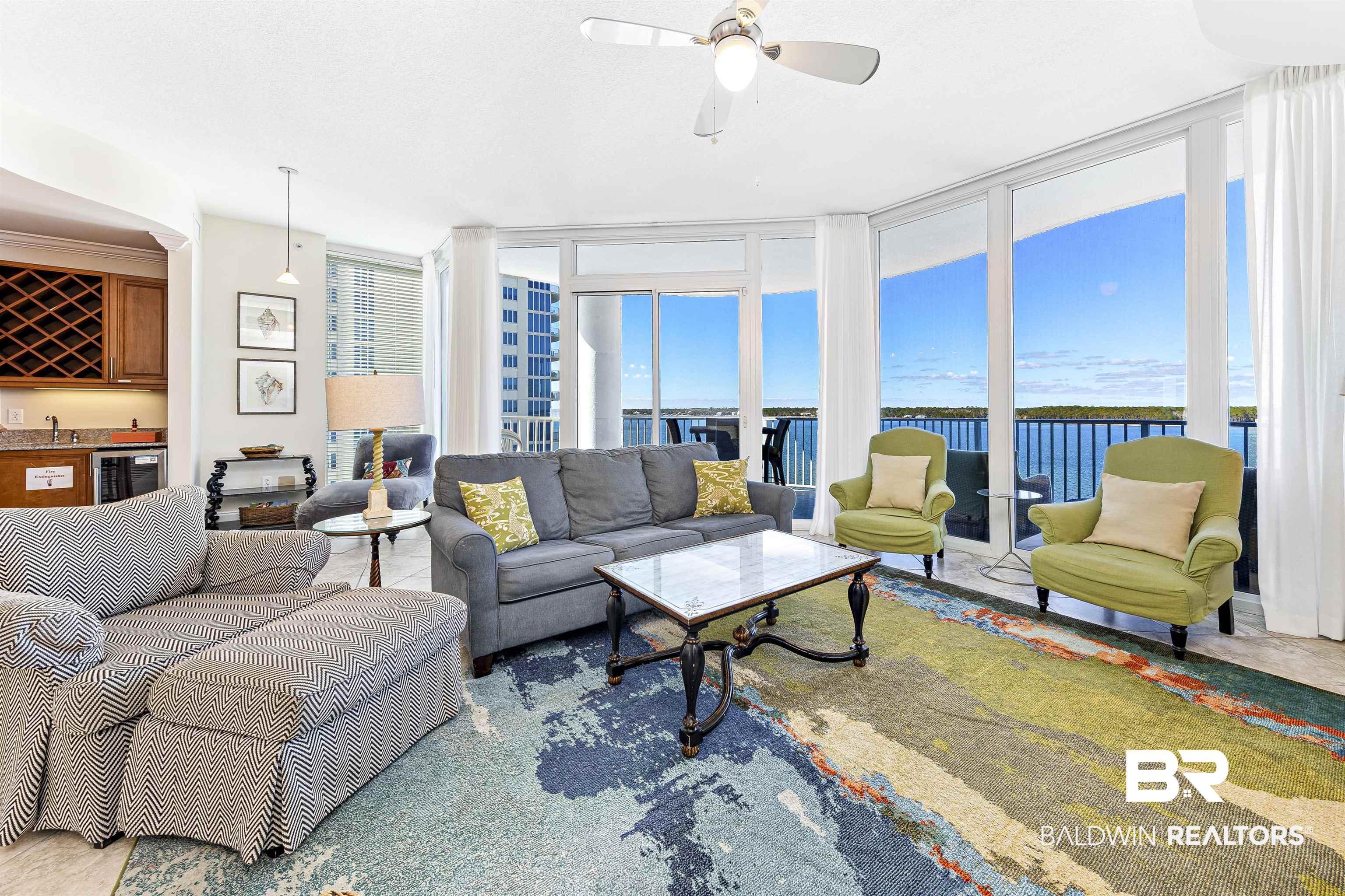 Image 2: Living room featuring expansive windows, wet bar, a ceiling fan, beverage cooler, and a water view