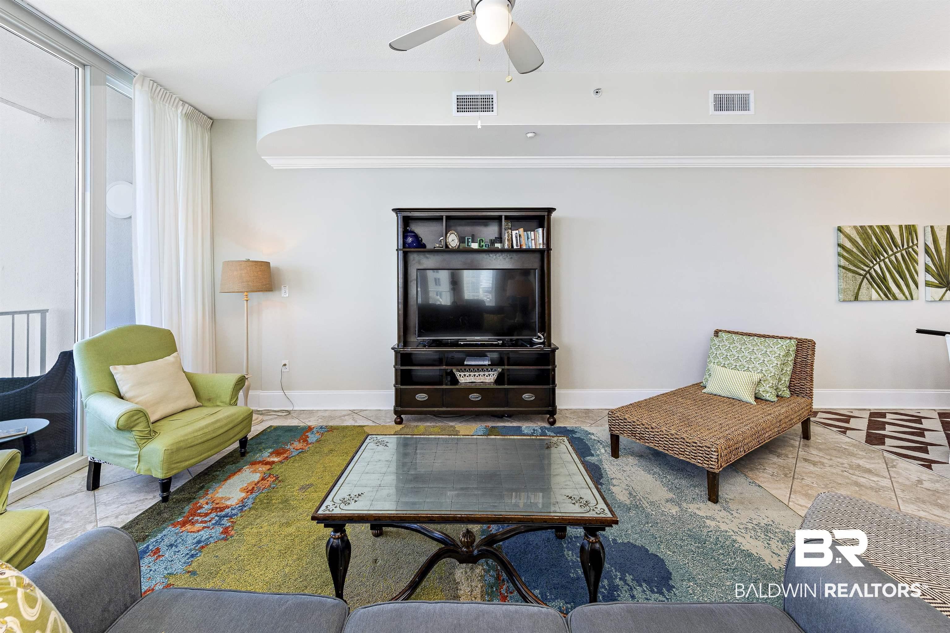 Image 4: Living area with a ceiling fan and tile patterned flooring