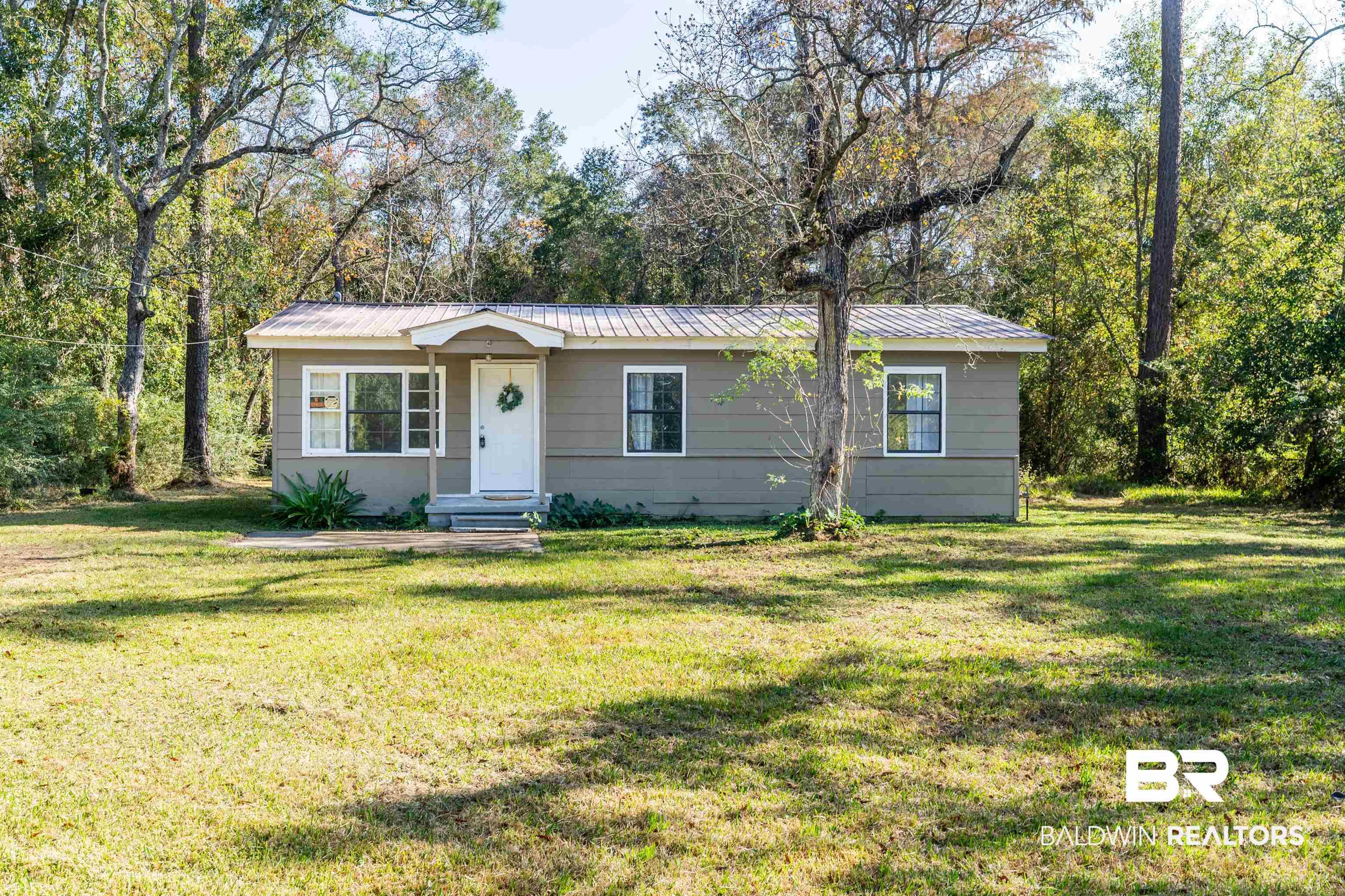 Image 2: Single story home with a metal roof and a front lawn