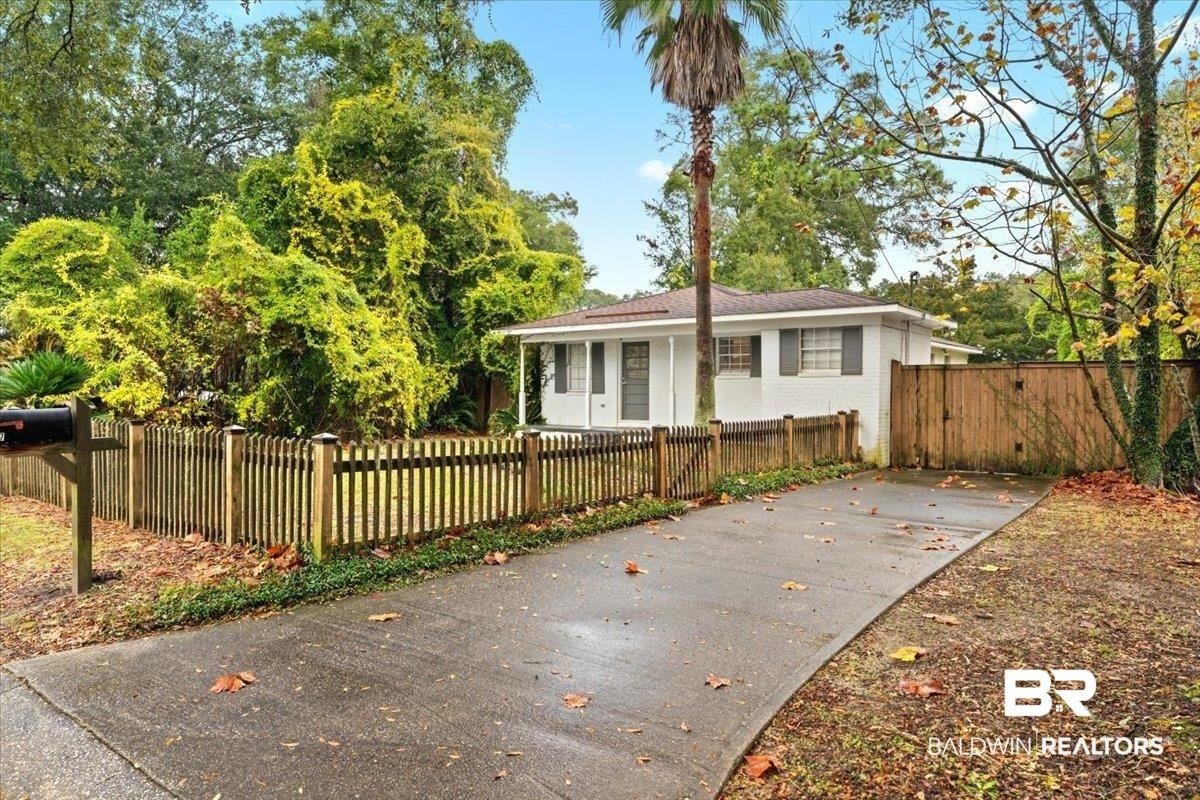 Image 1: View of front facade with a fenced front yard and brick siding