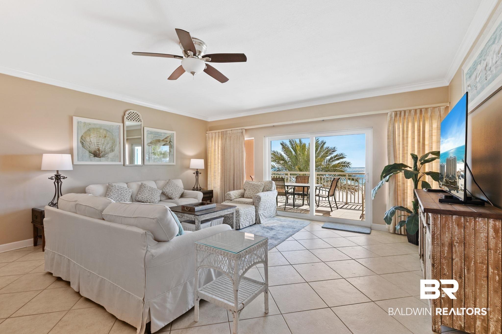 Image 2: Living area with a ceiling fan, ornamental molding, and light tile patterned floors
