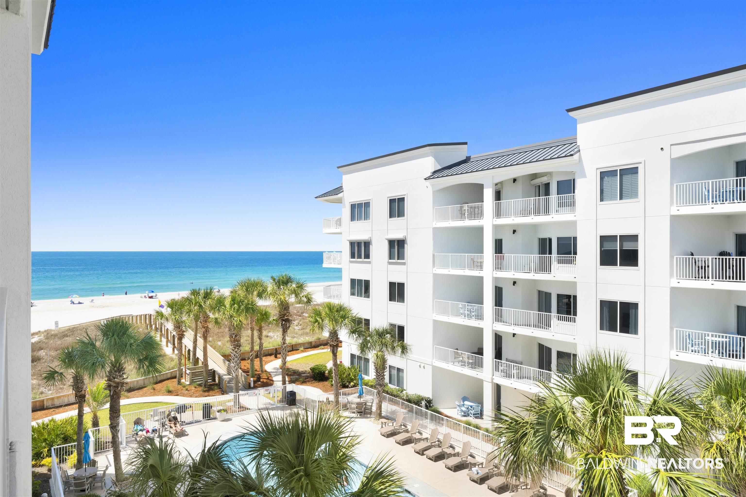 Image 2: Resort-style condominium complex featuring multiple balconies, a swimming pool, and direct beach access via a wooden boardwalk