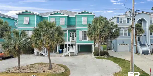 Image 2: Coastal-inspired residence featuring a vibrant teal exterior, a durable metal roof, and white shutters