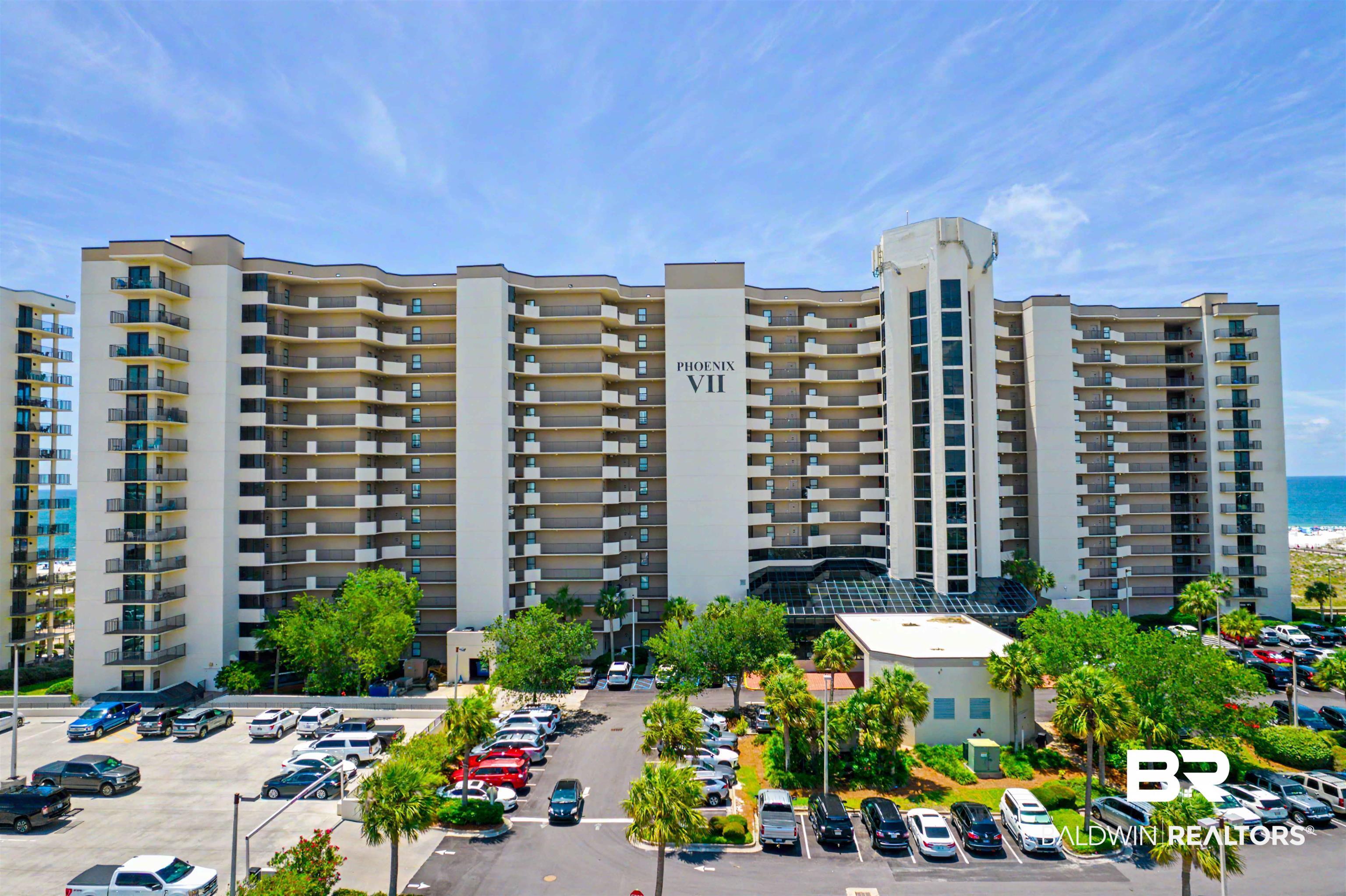 Image 2: Multi-story building featuring numerous private balconies, a prominent central architectural element, and a large parking area