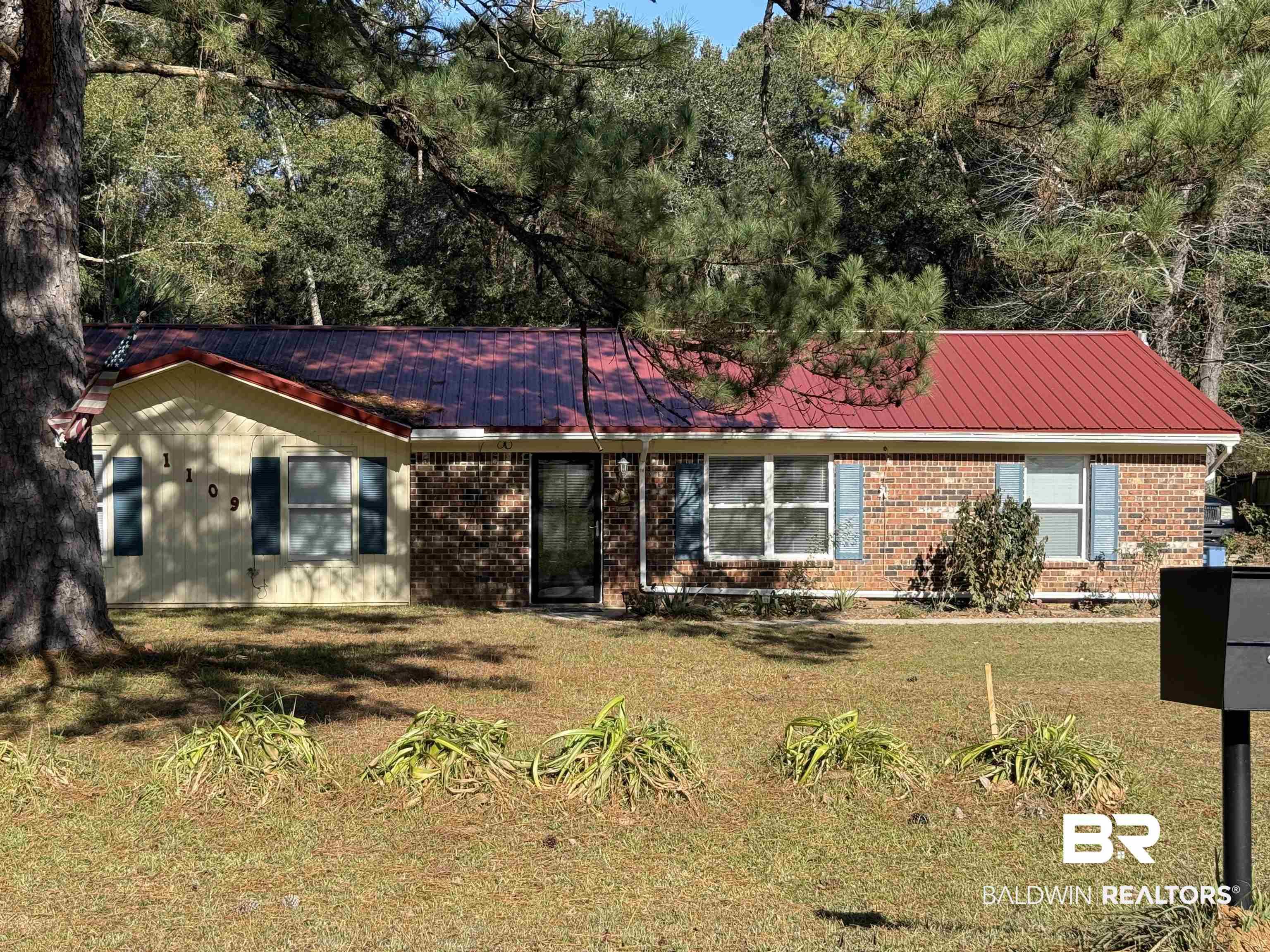 Image 3: Ranch-style home featuring a metal roof, a front lawn, and brick siding