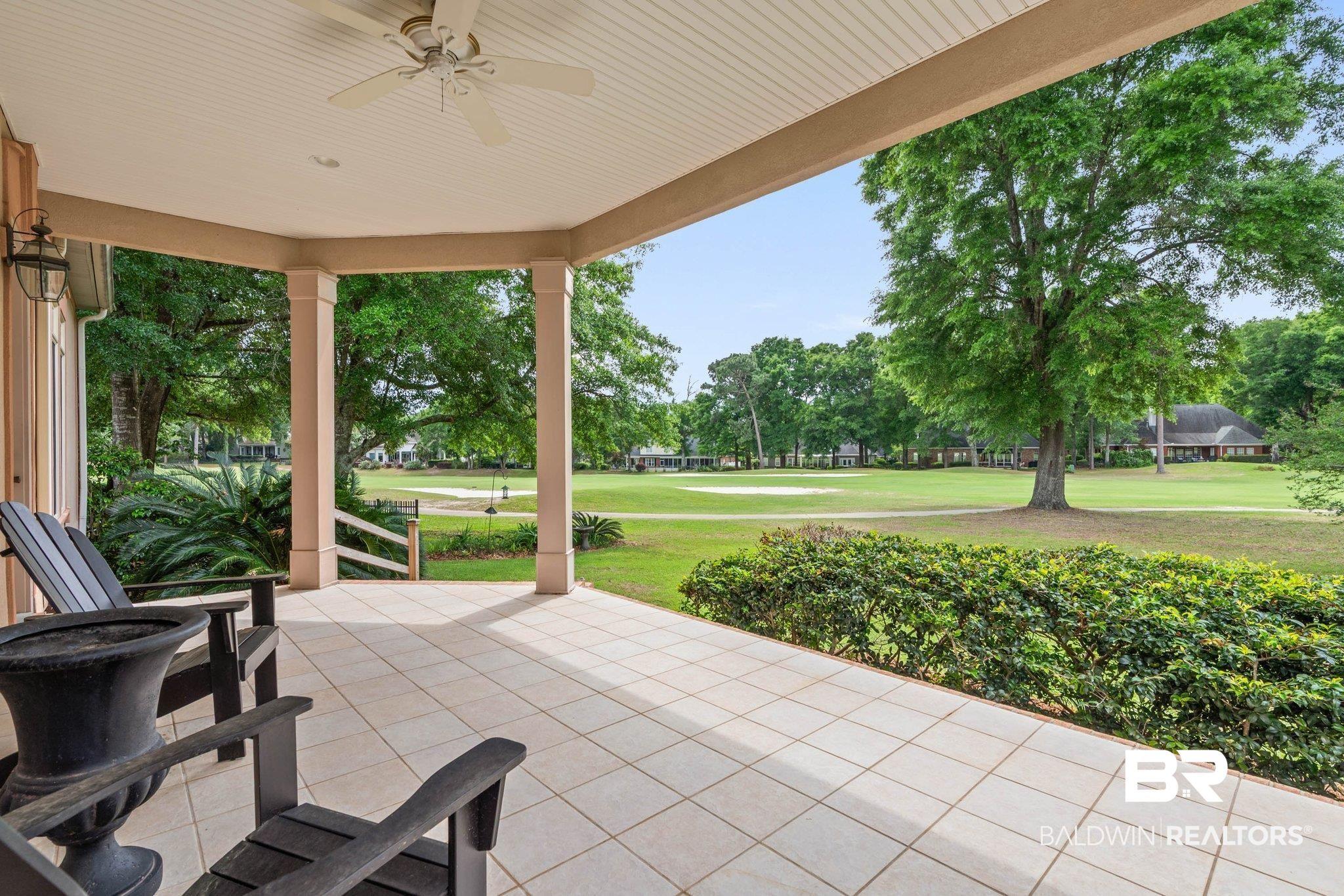 Image 4: Covered outdoor patio featuring light-toned square floor tiles, a ceiling fan, and decorative outdoor lighting