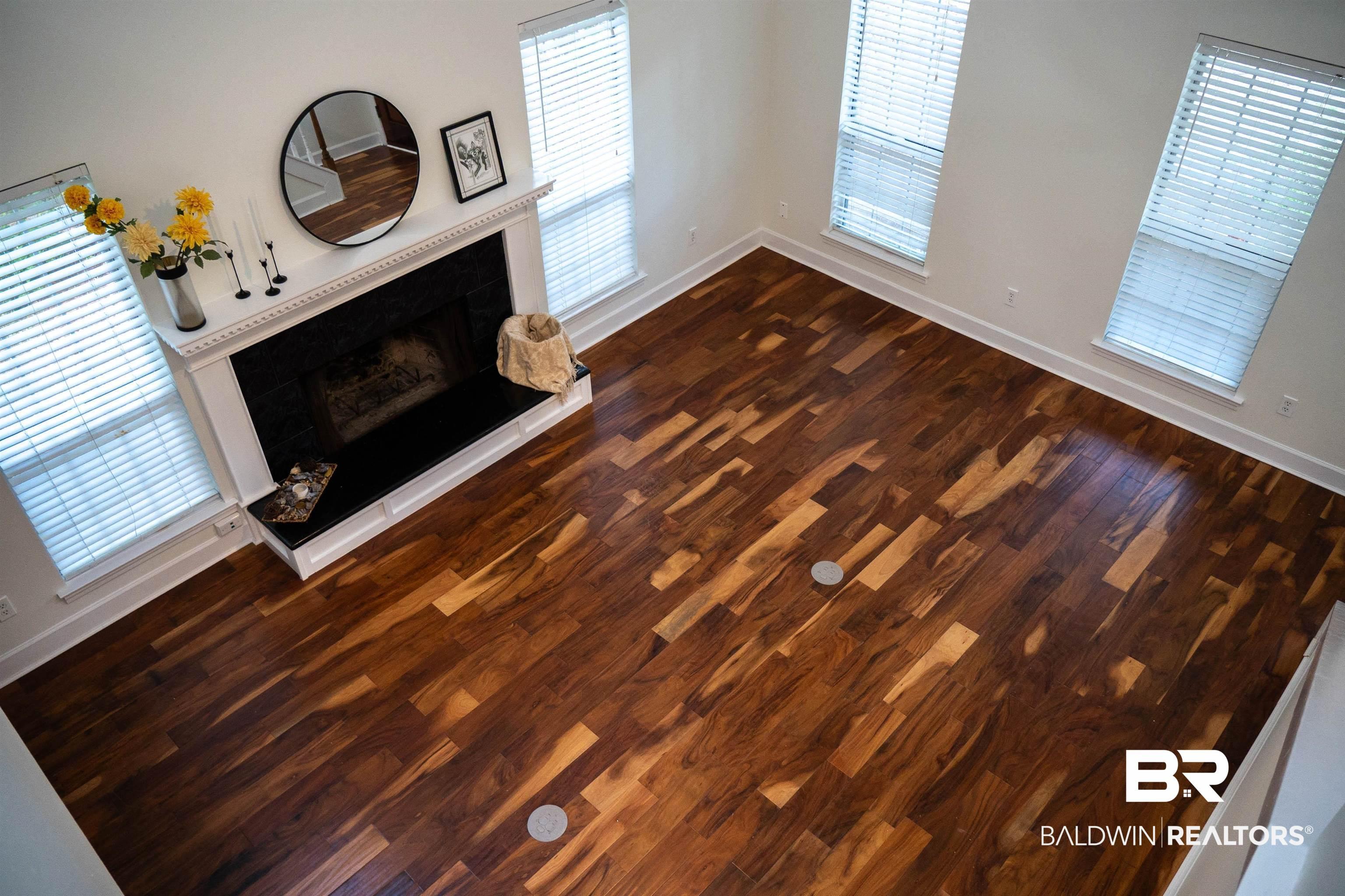 Image 4: Spacious room featuring rich wood-finish flooring, a prominent fireplace with a white mantel, and multiple windows providing natural light