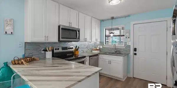 Image 4: Kitchen featuring white cabinets, a peninsula, stainless steel appliances, a breakfast bar, and a textured ceiling