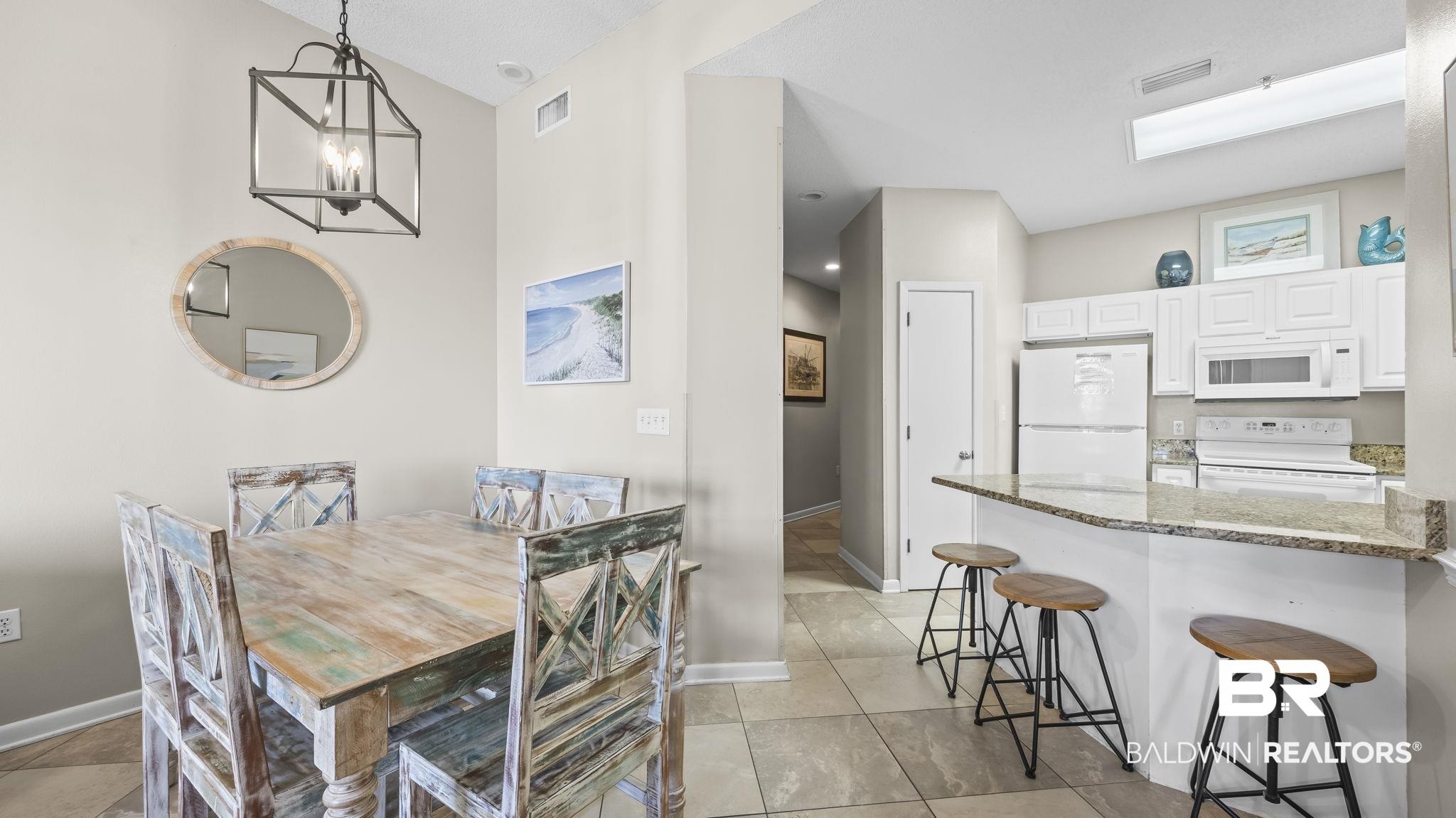 Image 4: Dining space featuring suspended lighting and light tile patterned flooring