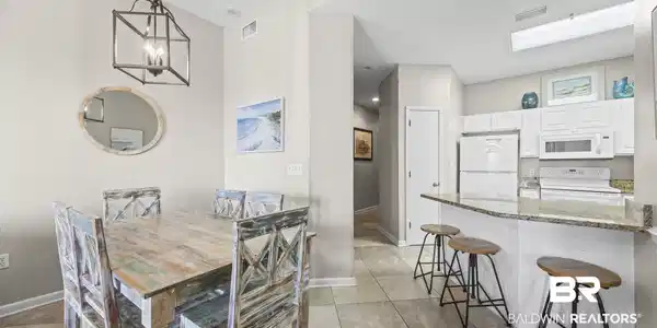 Image 4: Dining space featuring suspended lighting and light tile patterned flooring