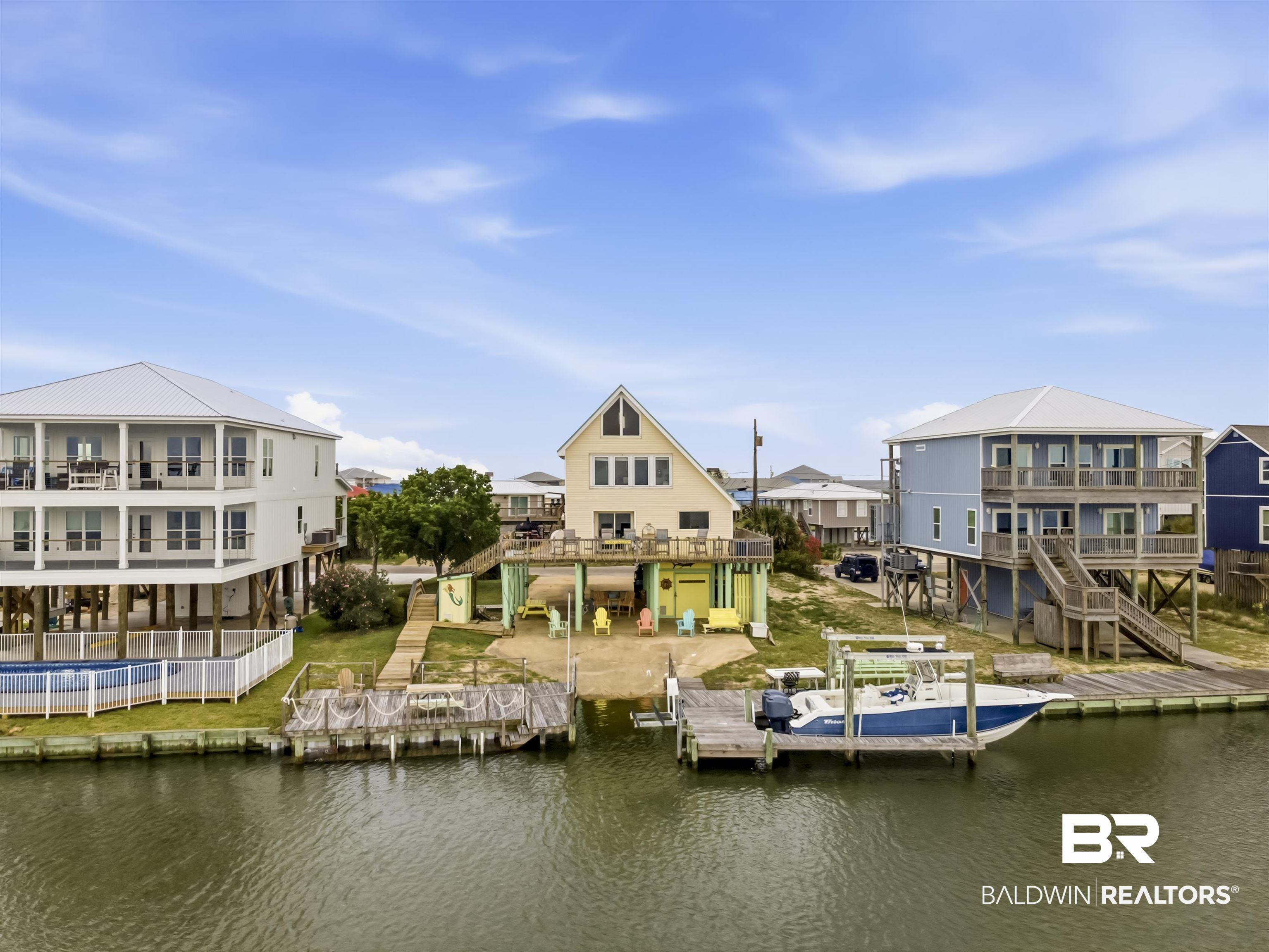 Image 1: Canal-front property featuring a private boat dock, elevated construction, a metal roof, and an exterior staircase