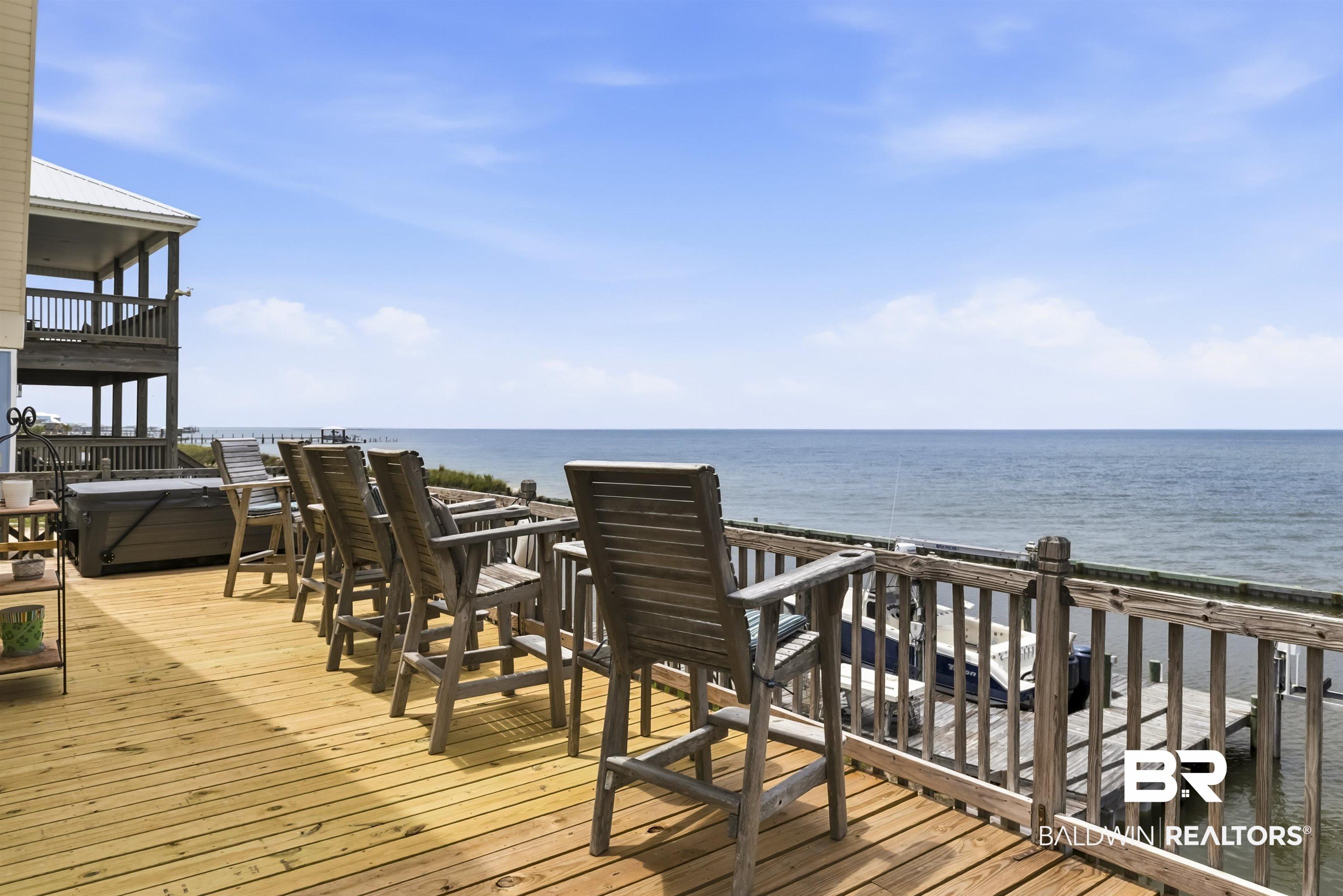 Image 3: Expansive waterfront deck featuring natural wood flooring and a wooden railing system