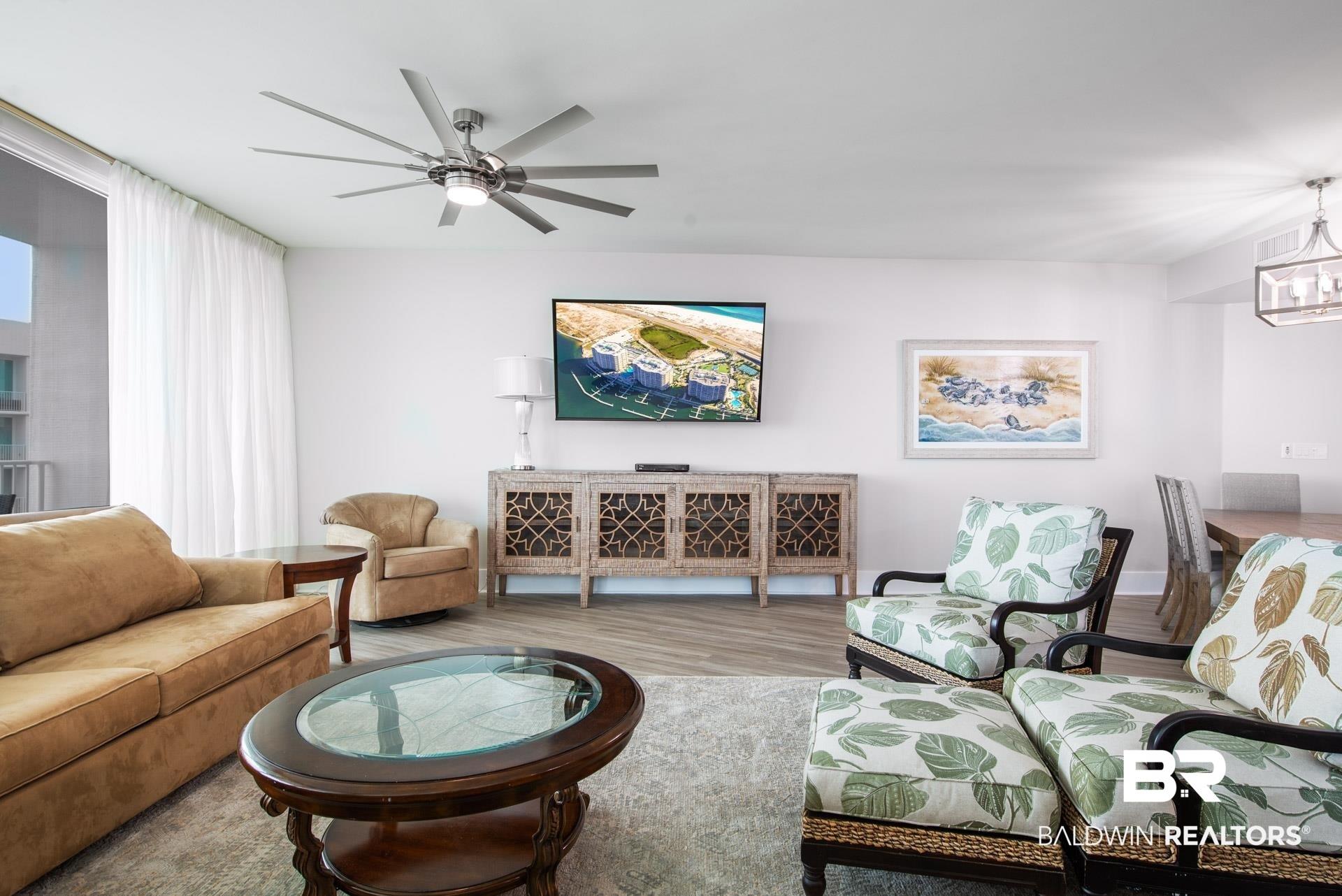 Image 4: Living room with ceiling fan with notable chandelier and light hardwood / wood-style flooring