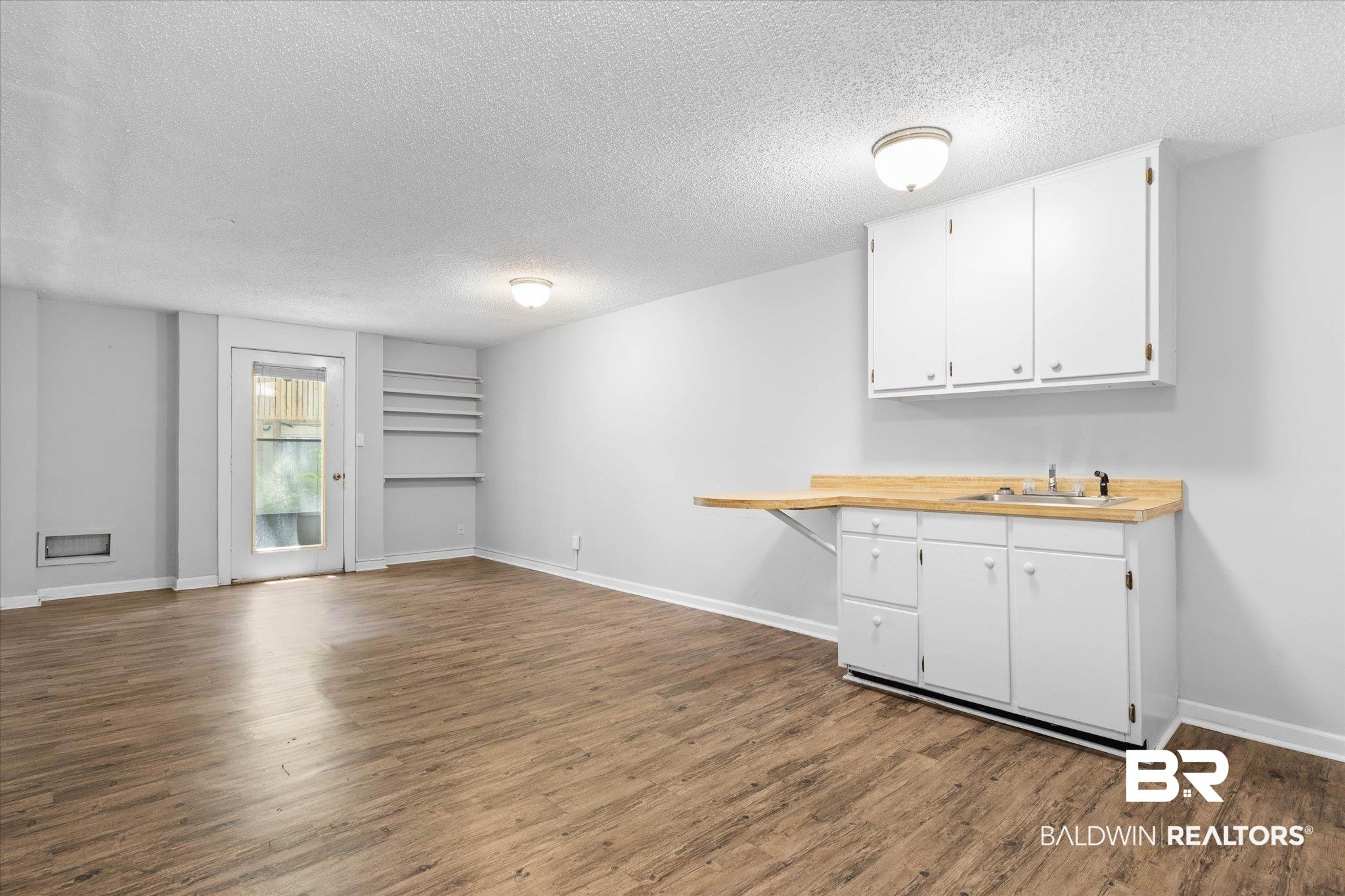 Image 3: Kitchen with a textured ceiling, dark wood-type flooring, white cabinets, butcher block countertops, and open floor plan