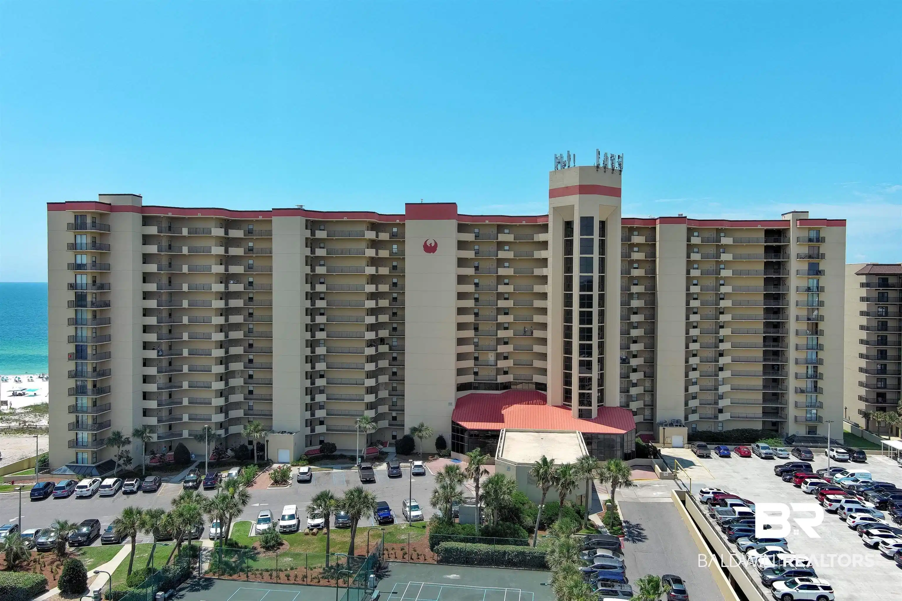 Image 1: Multi-story condominium building featuring extensive private balconies, a prominent central entrance tower, and mature palm landscaping