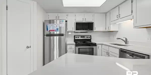 Image 4: Kitchen with white cabinetry, stainless steel appliances, white subway tile backsplash, and light-toned countertops