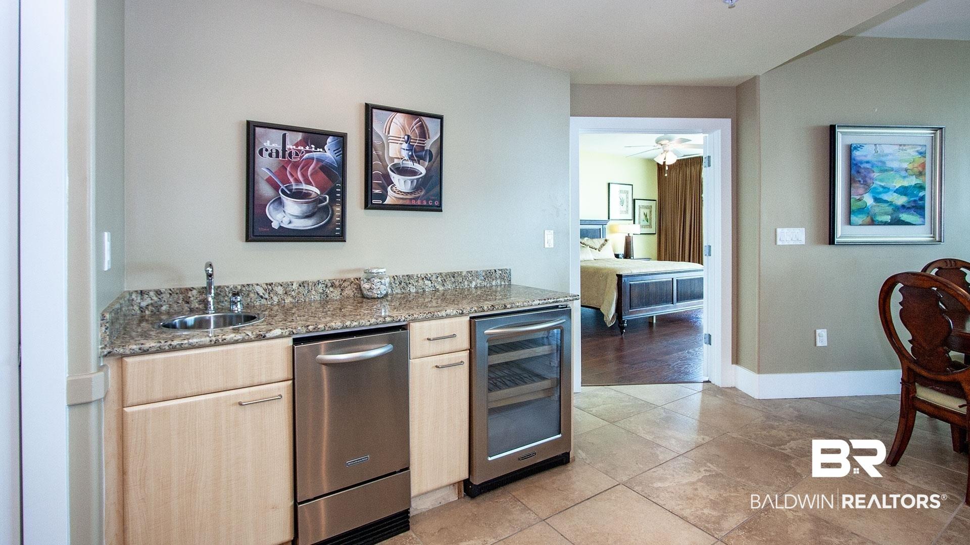 Image 4: Kitchen featuring wine cooler, a sink, light brown cabinets, stainless steel dishwasher, and light stone countertops