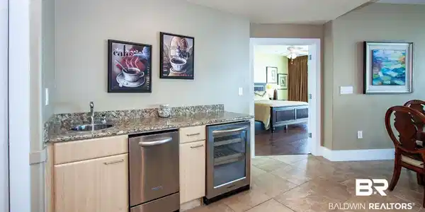 Image 4: Kitchen featuring wine cooler, a sink, light brown cabinets, stainless steel dishwasher, and light stone countertops