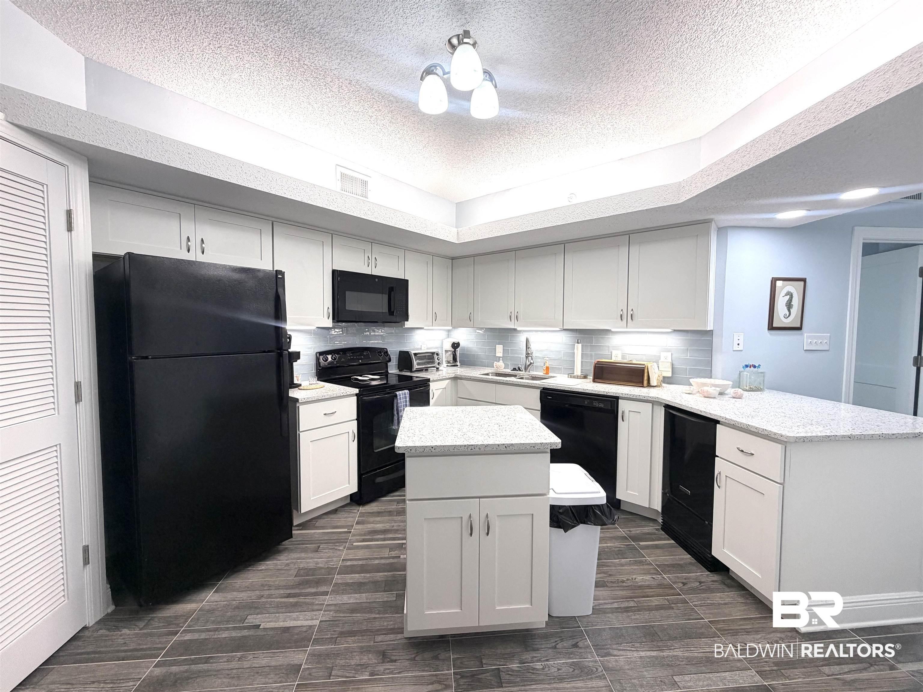 Image 2: Kitchen featuring black appliances, a peninsula, white cabinets, backsplash, and a textured ceiling