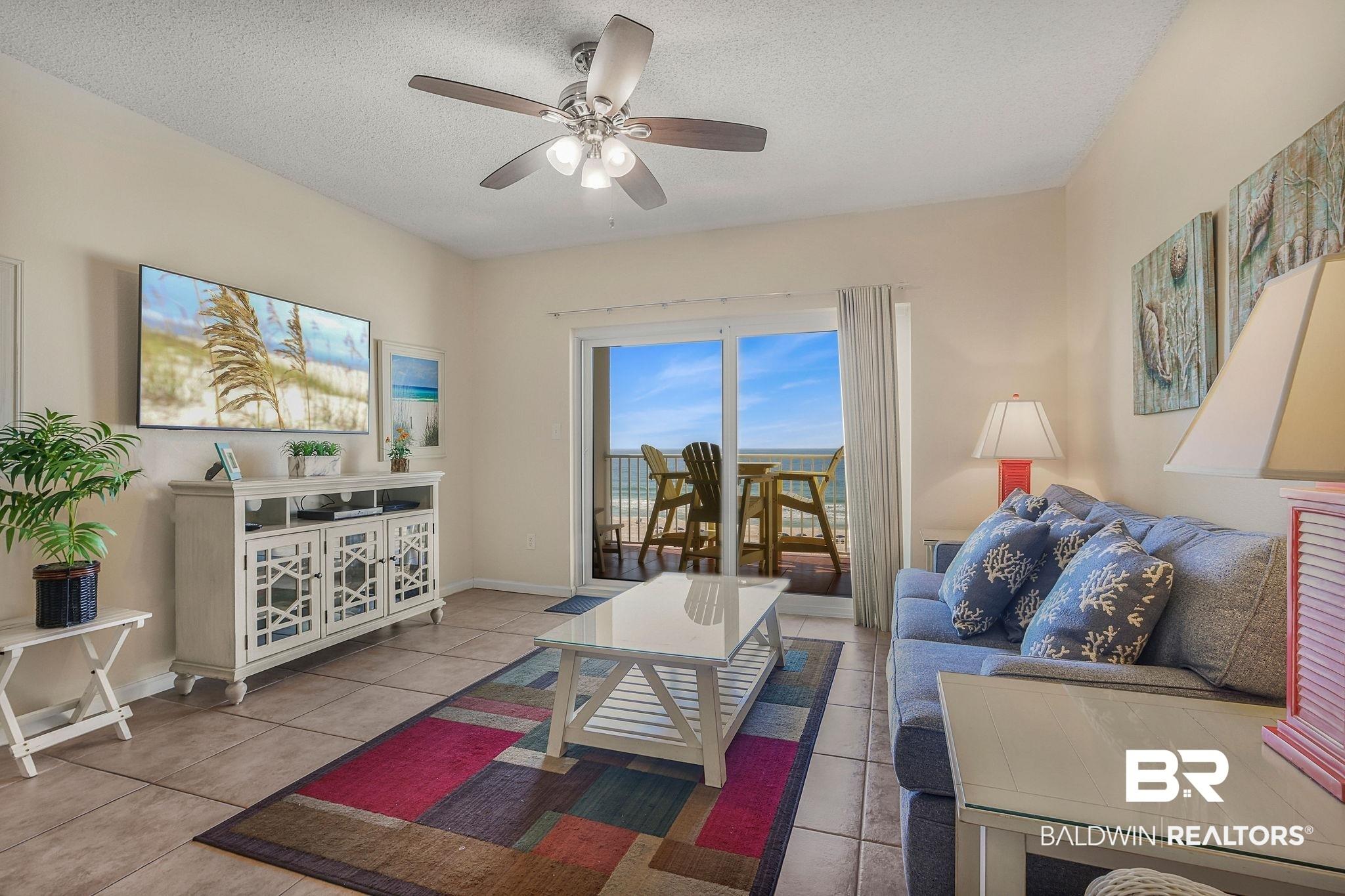 Image 2: Living area with ceiling fan, light tile patterned flooring, and a textured ceiling